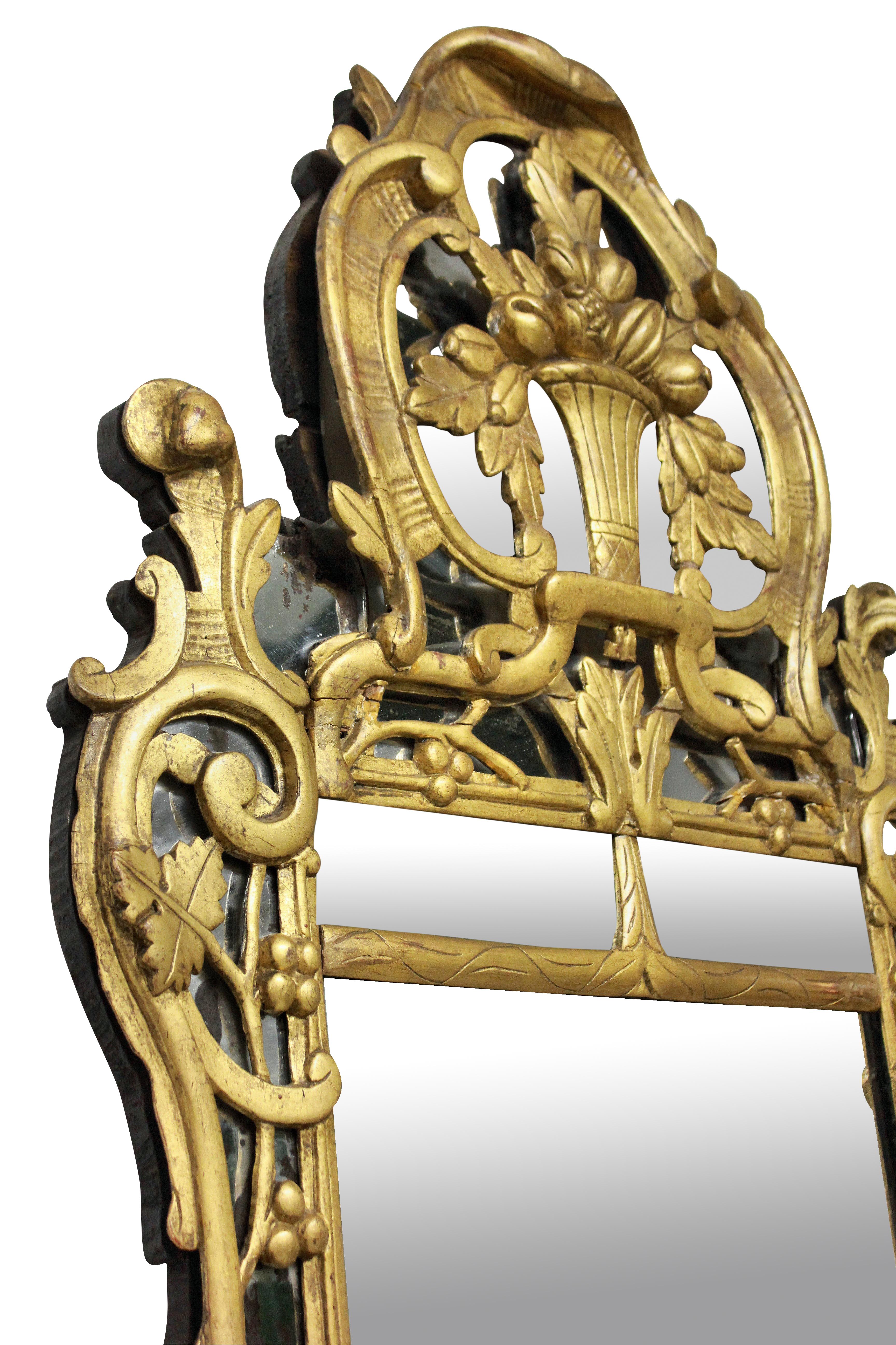 A French Provincial mirror in carved giltwood, depicting foliage, with its original mercury plate. There is distressing around the edges but not in the middle of the mirror plate.

  