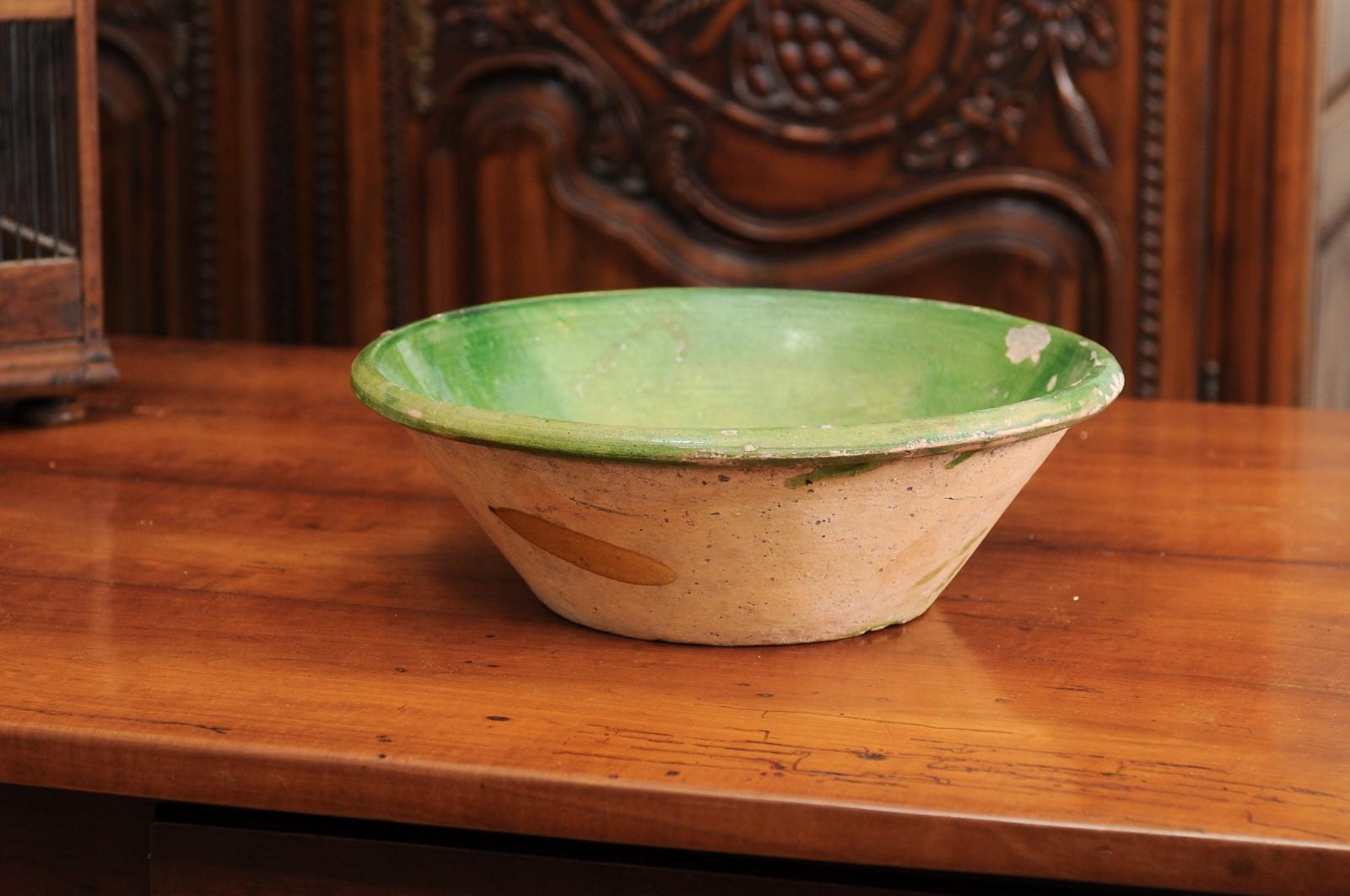 A French Provincial green glazed pottery bowl from the mid-19th century, with unfinished belly. Created in France during the reign of Emperor Napoléon III, this pottery bowl features a circular body, boasting a green glaze on the interior, while the