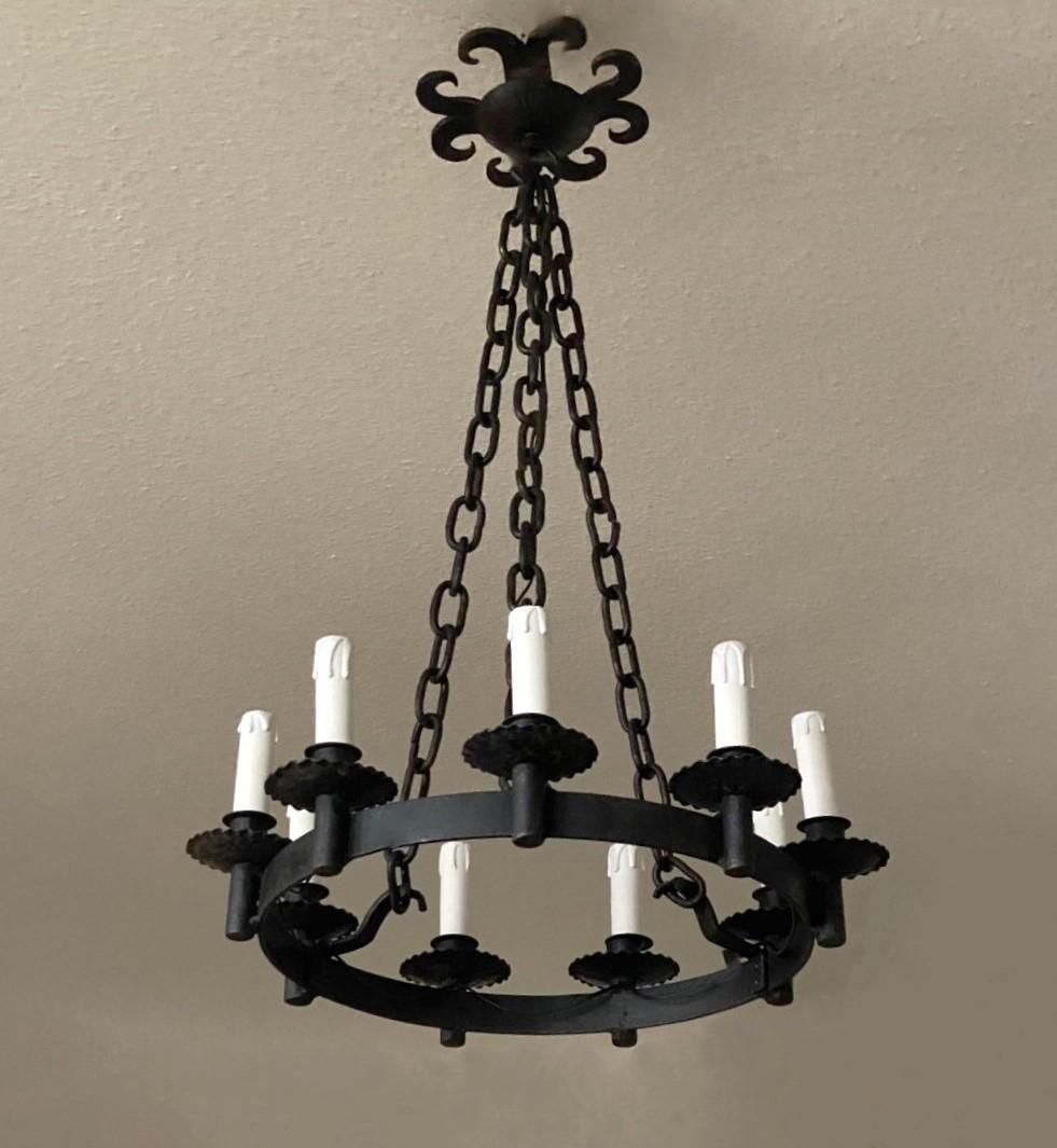 Very elegant French Provincial style hand-forged iron chandelier, France, 1890-1900. Large ring supporting nine candelabra lights, suspended by three iron chains conecting to a large iron ceilinling rosette.
In very good condition, no damages,