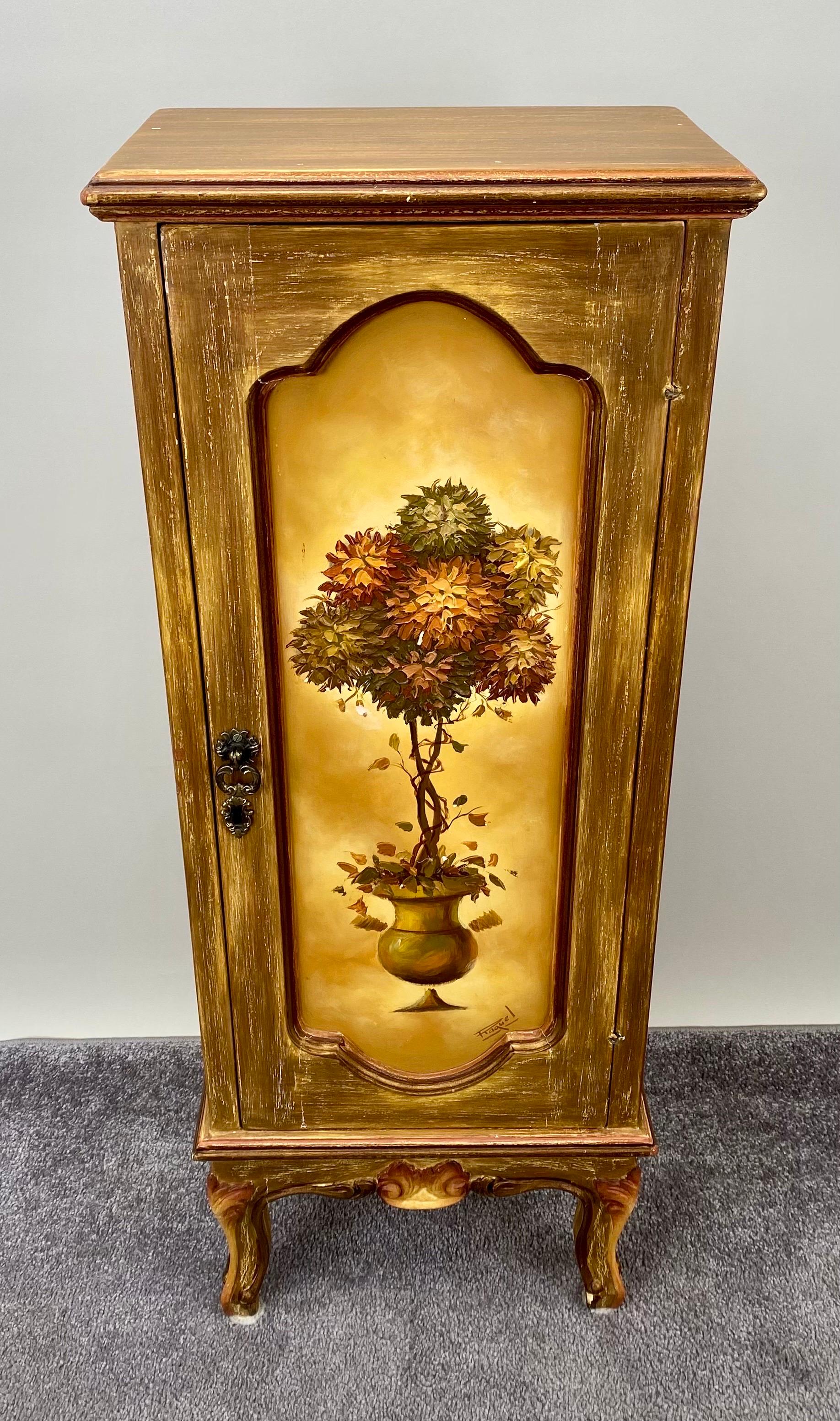  A French Provincial  one-door nightstand, a testament to the artistry and craftsmanship that define the allure of this classic piece. The door itself stands as a canvas of hand-painted splendor, depicting a delicate tree or plant within a