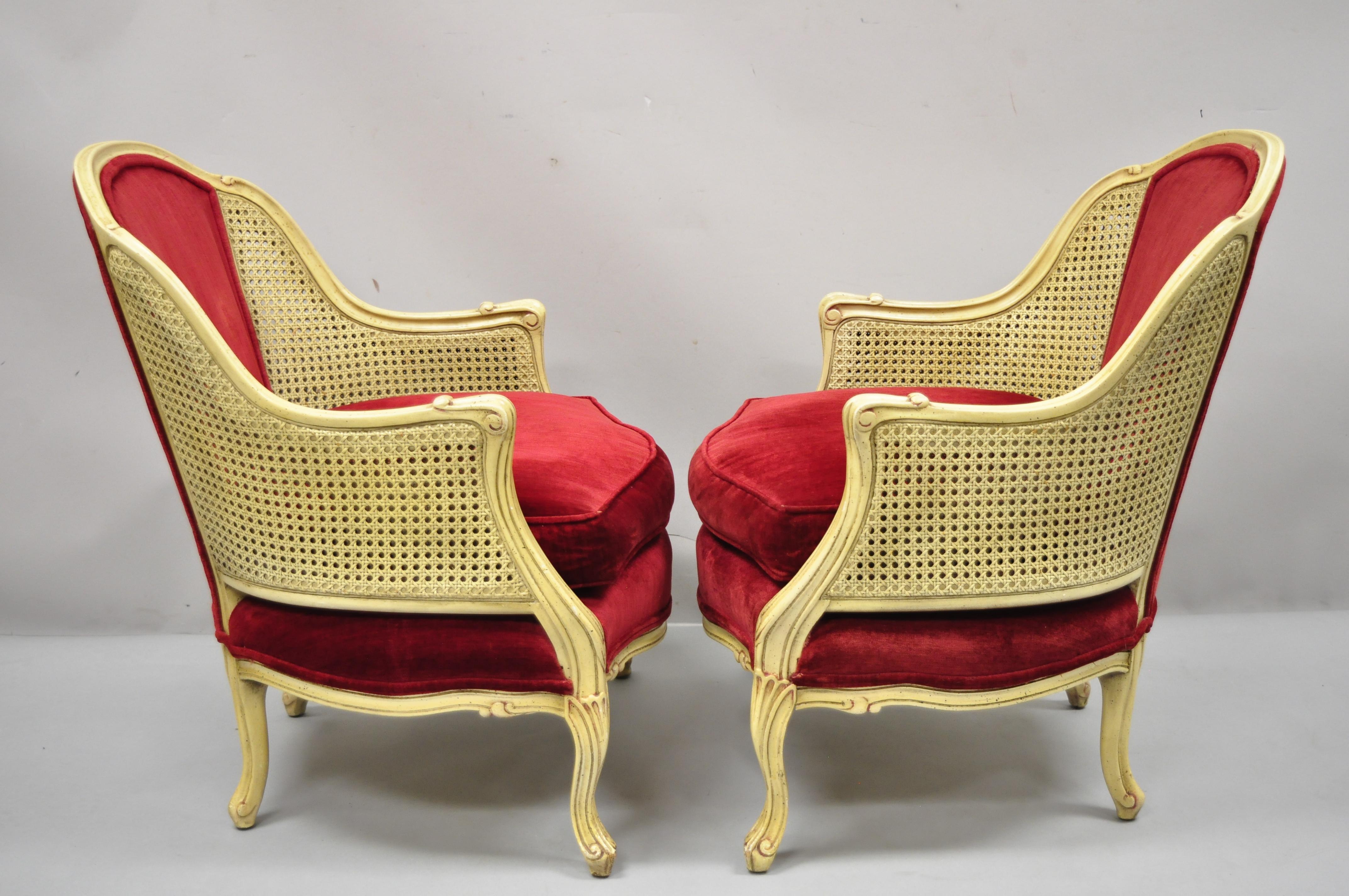 Vintage French Provincial Hollywood regency cream and red cane bergère club arm chairs, a pair. Item features double cane sides, cream painted finish, red upholstery, solid wood frames, cabriole legs, very nice vintage pair, great style and form,