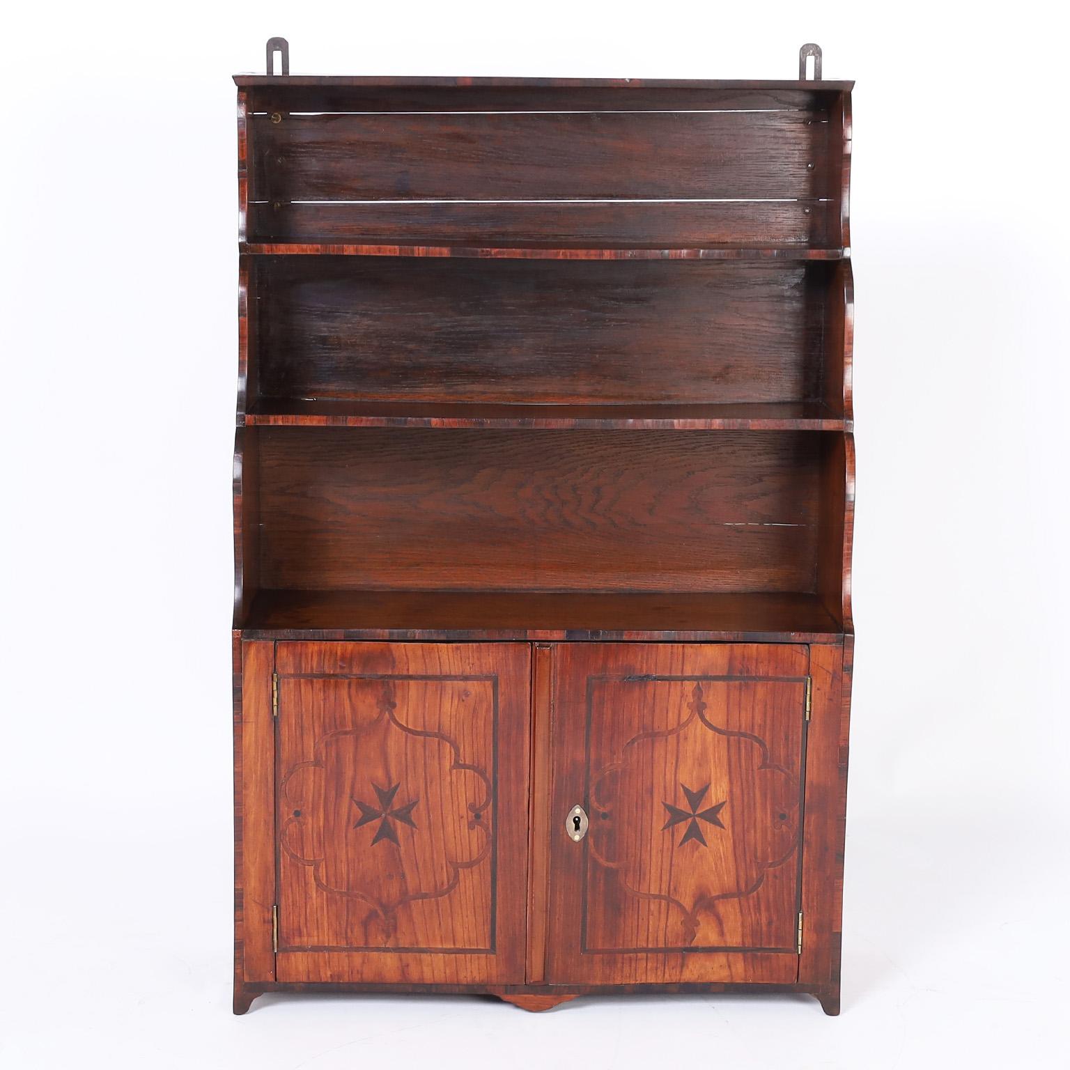 Rare and unusual 18th century petite cupboard crafted in well grained fruitwood in a step down form with a cabinet below, having rosewood inlays that accentuate the graceful lines, set on tapered feet and can be hung by metal brackets.