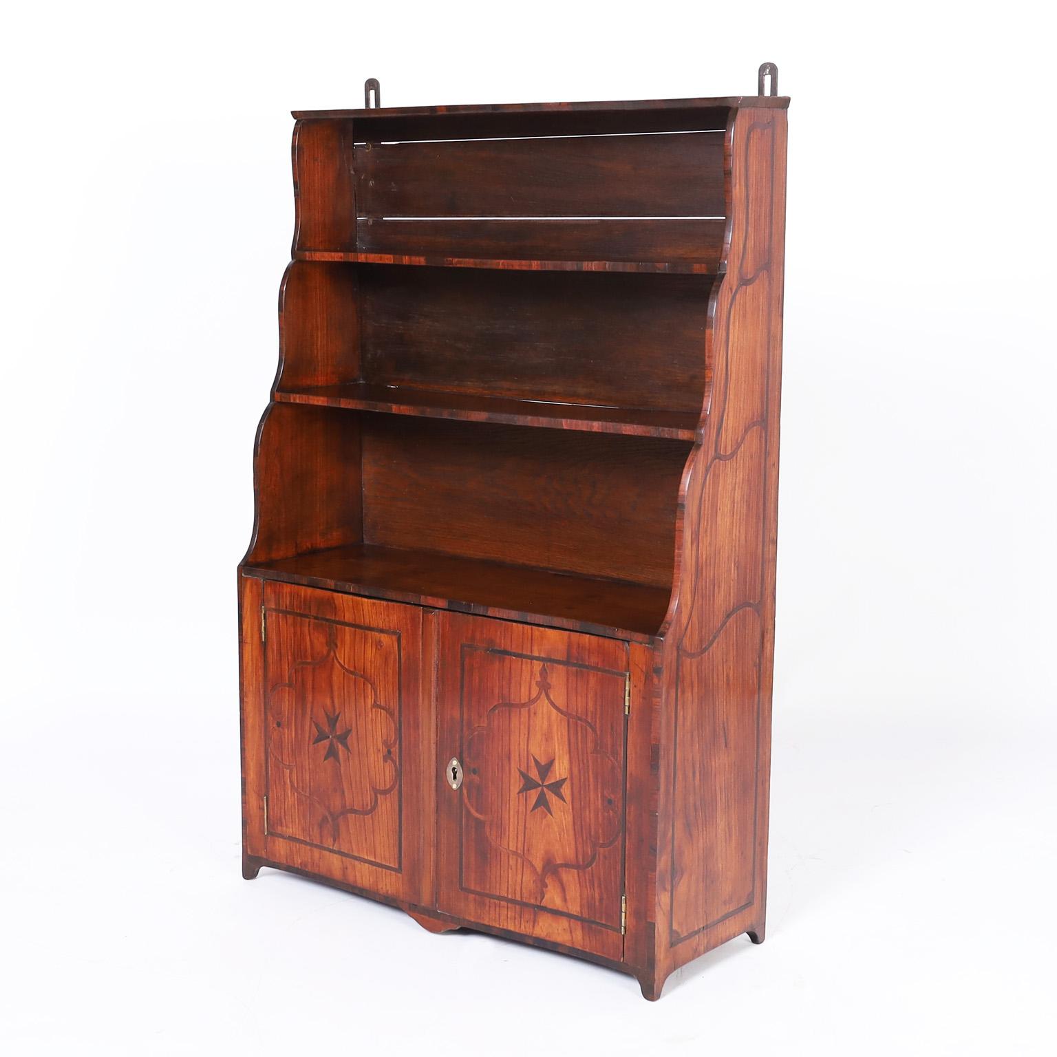 Rare and unusual 18th century petite cupboard crafted in well grained fruitwood in a step down form with a cabinet below, having rosewood inlays that accentuate the graceful lines, set on tapered feet and can be hung by metal brackets.