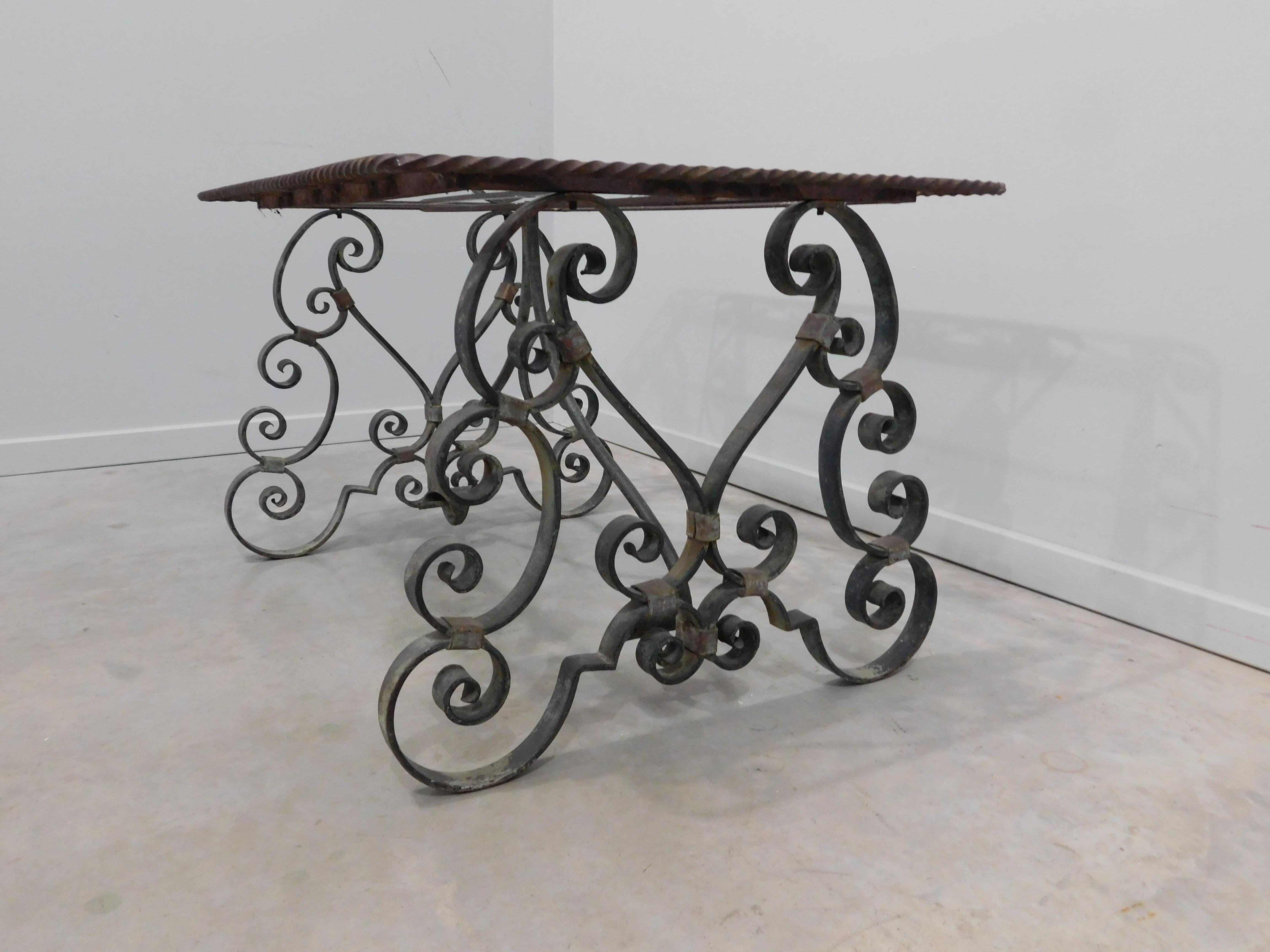 French Provincial verde green wrought iron occasional or coffee table. Rectangular glass top table within c and s-scrolled hand-forged iron frame, supported on an elaborate hand-forged iron base with scrolled legs and spreaders.French Provincial or