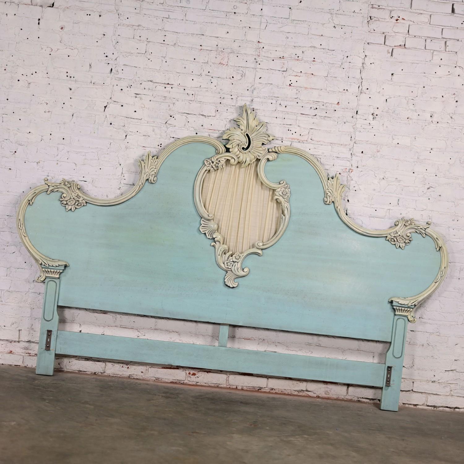 Gorgeous vintage French Provincial Renaissance style king sized headboard with antiqued powder blue ceruse factory finish & heavy carved off-white trim details including leaves, vines, & floral elements, & a center cutout with ruched fabric attached