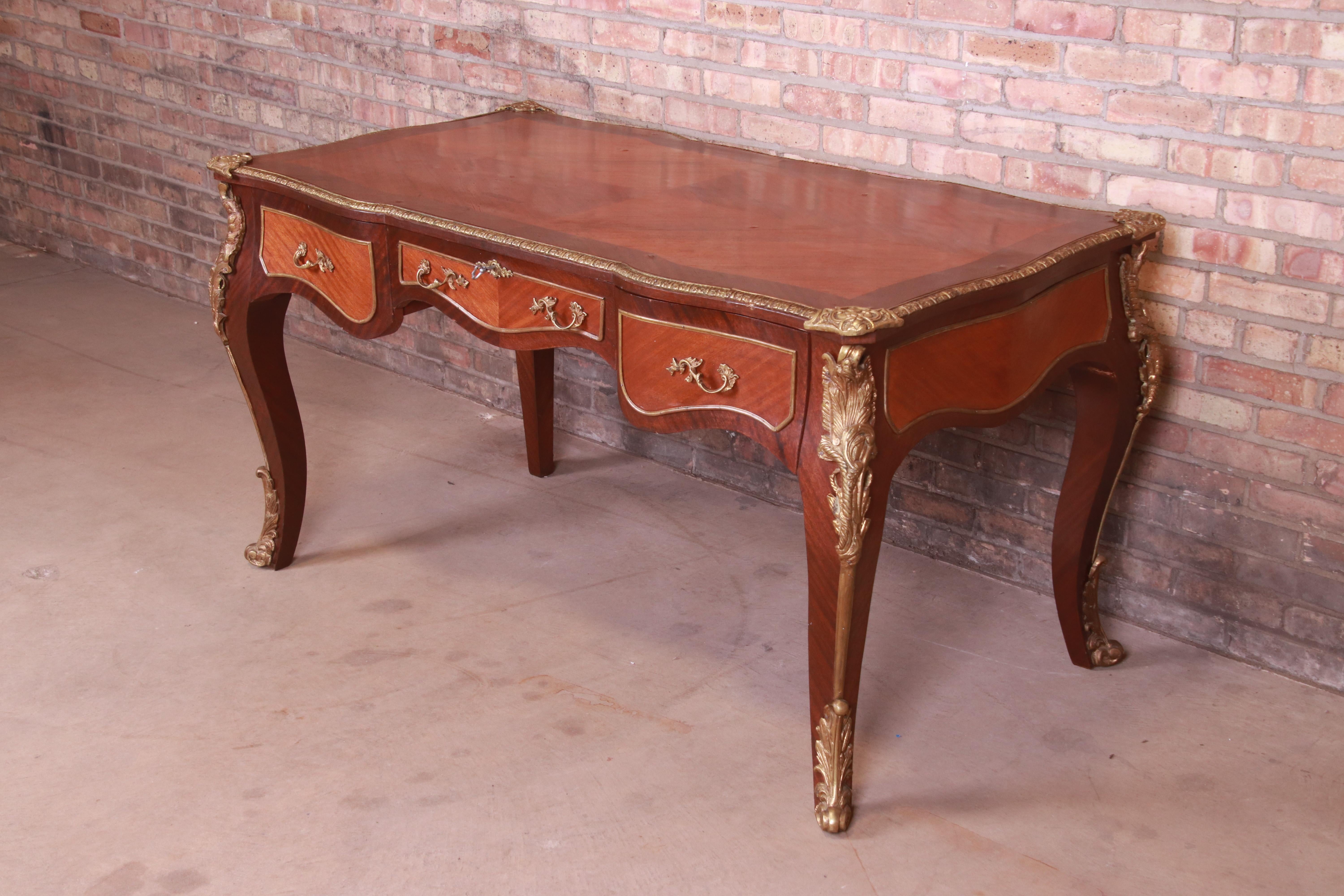 A gorgeous French Provincial Louis XV style executive writing desk or bureau plat desk

France, early 20th century

Mahogany with satinwood inlay, and original brass trim and ormolu.

Measures: 60.5