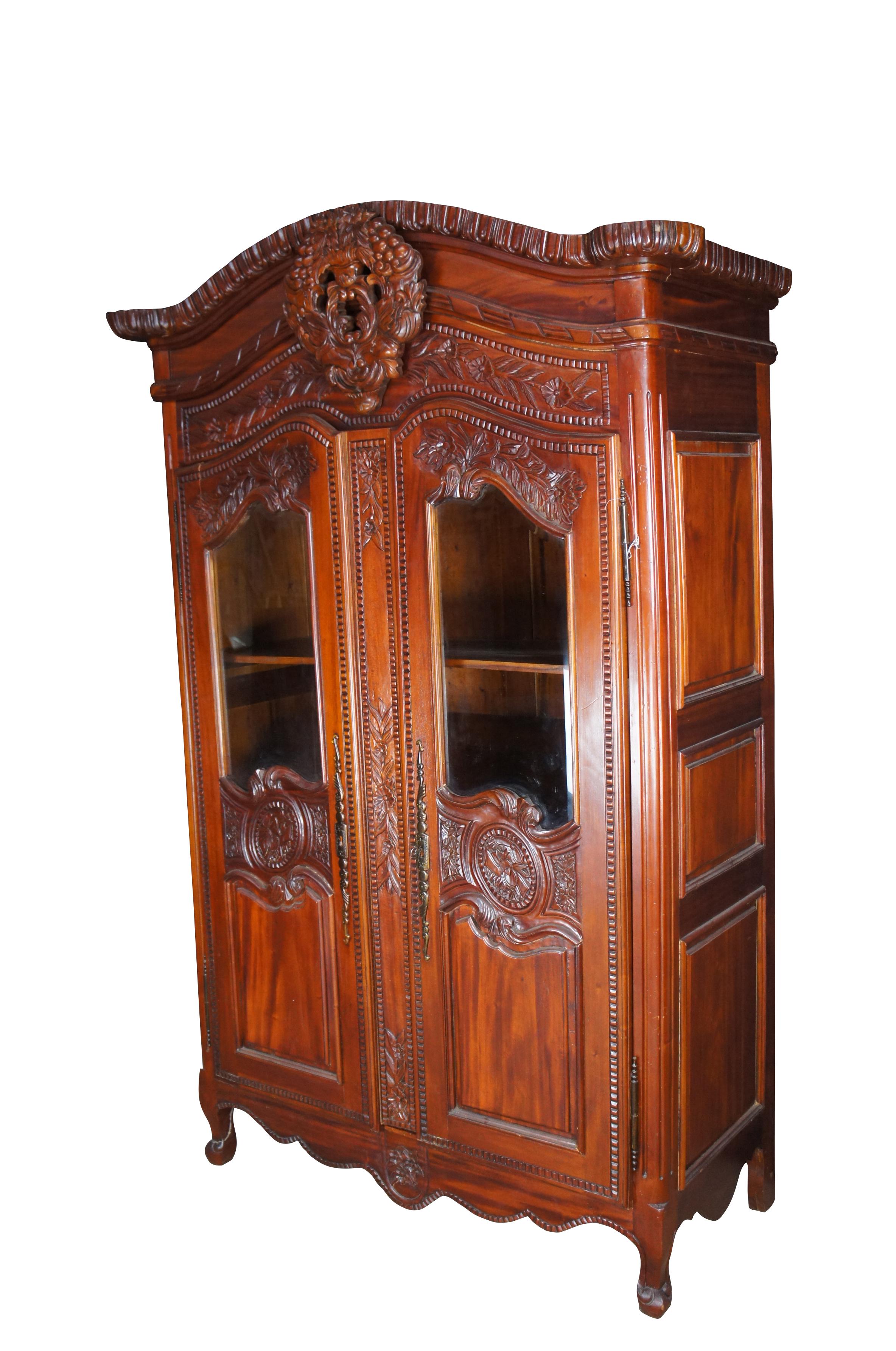 Vintage French Louis XV / Provincial style wedding armoire / wardrobe / linen press or display cabinet, circa last quarter 20th century. Made of mahogany featuring baroque styling with a carved crown over a floral bird theme.  The armoire has
