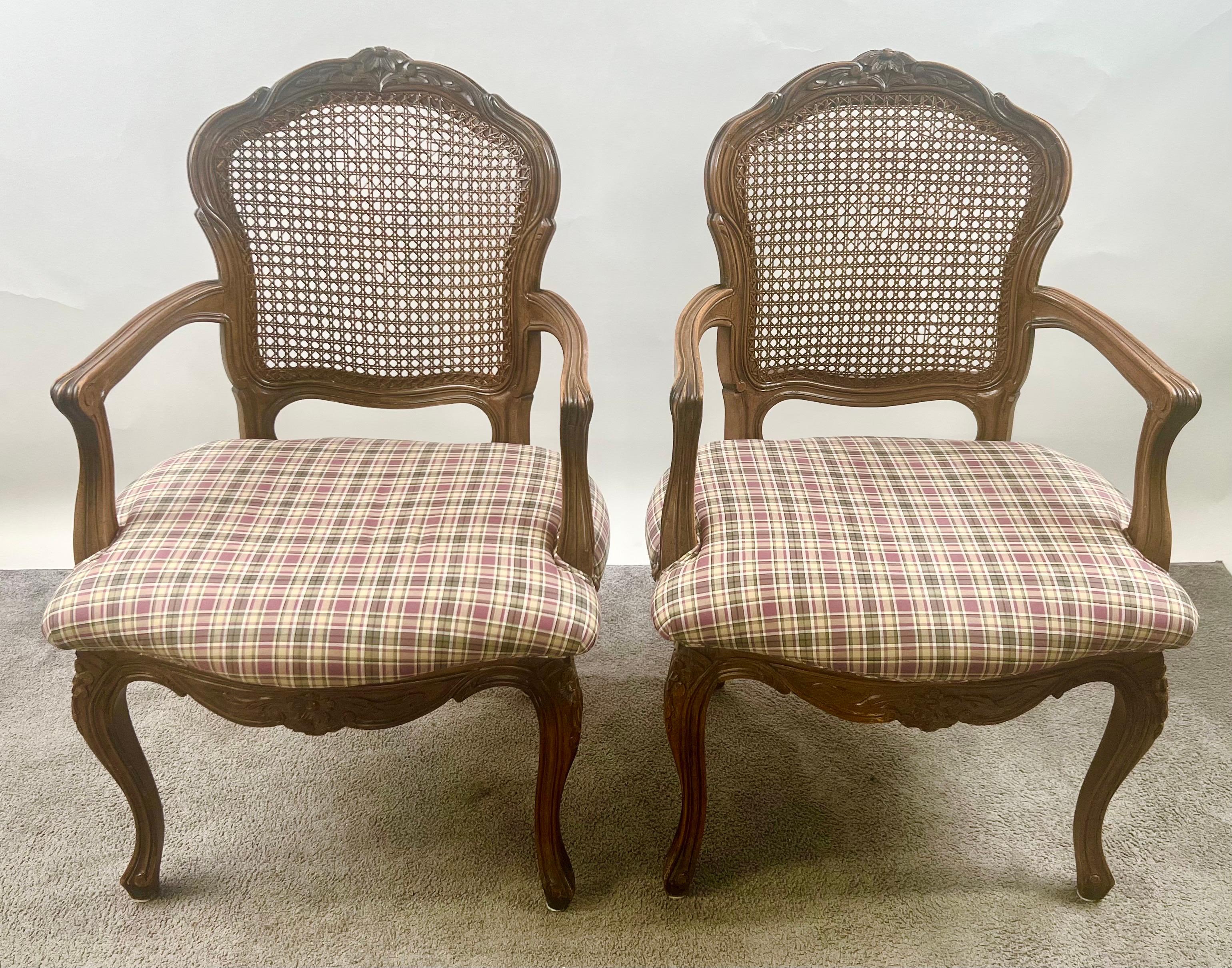 French Provincial Louis XV Style Cane Back with Plaid Upholstery Chair, a Pair: 
A charming pair of French Provincial armchairs inspired by the Louis XV style. Each chair features a gracefully carved wooden frame with a shaped crest rail and flowing
