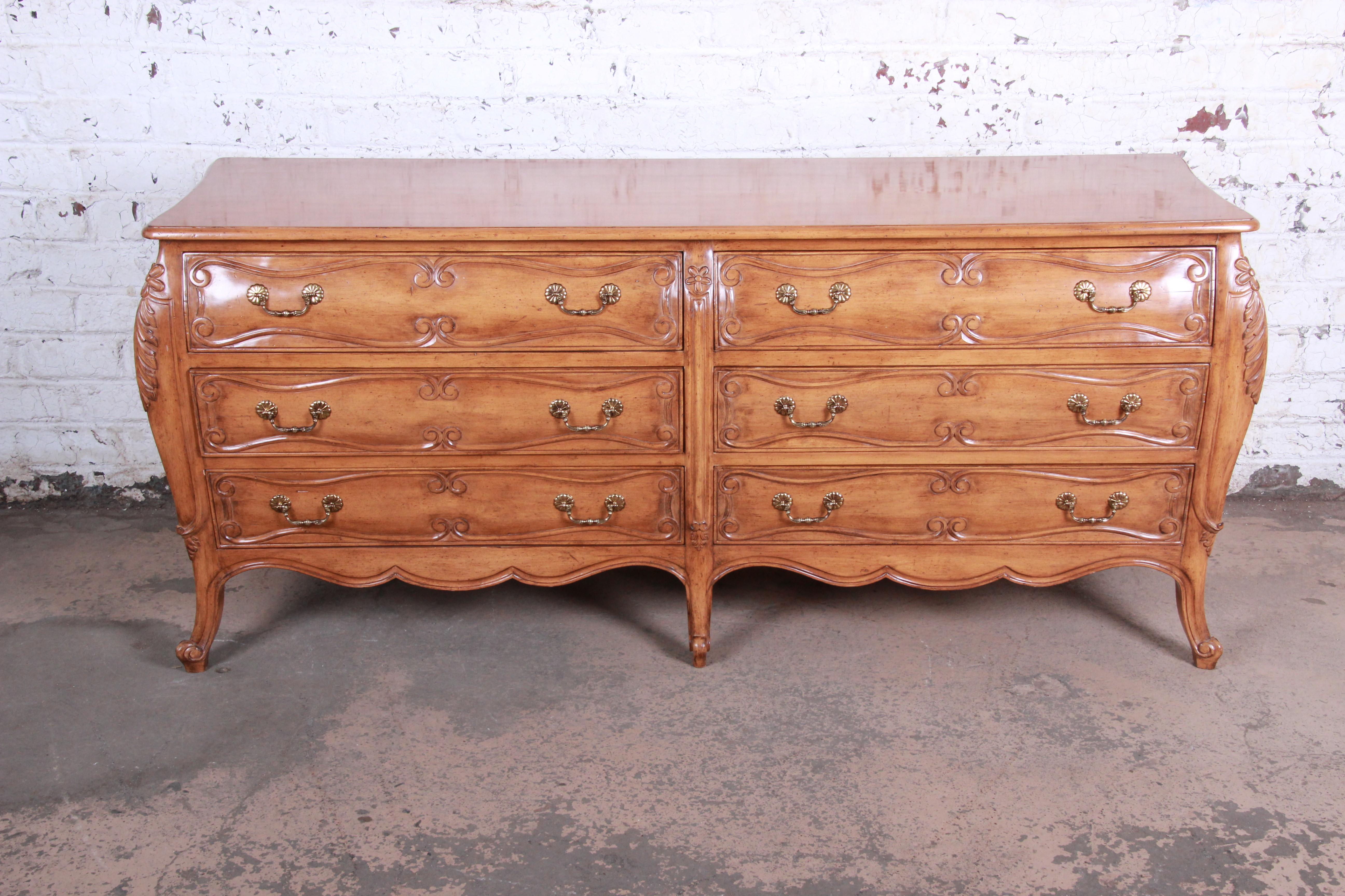 A gorgeous French Provincial Louis XV style carved fruitwood double dresser. The dresser features beautiful wood grain, with nice carved wood details and cabriole legs. It offers ample storage, with six drawers. Hardware is original. The dresser is