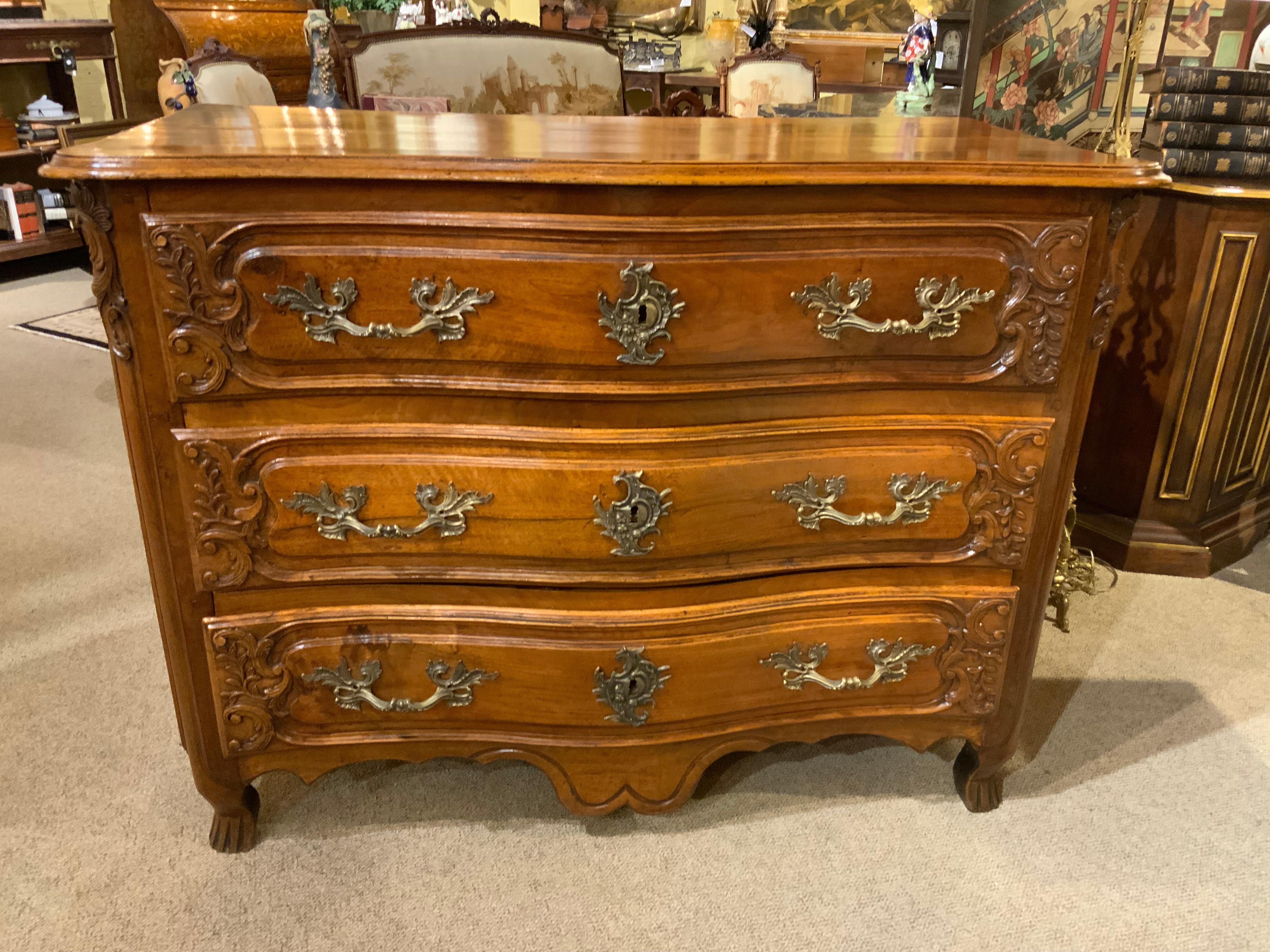 Questa raffinata commode in noce intagliato in stile Luigi XV ha una forma
Il piano, su tre cassetti con accenti foliati a volute, si eleva su 
Piedi a staffa scanalati. È del 18° secolo ed è intagliato a mano.