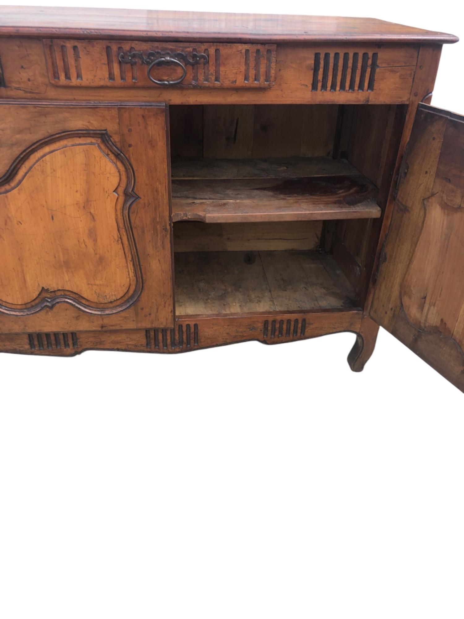 Un pezzo d'antiquariato in stile French Provincial Louis XV, con una patina rustica calda e ben invecchiata e ferramenta originale. Realizzato in Francia all'inizio del XIX secolo, presenta il piano originale in tavole con bordo modanato, sopra una