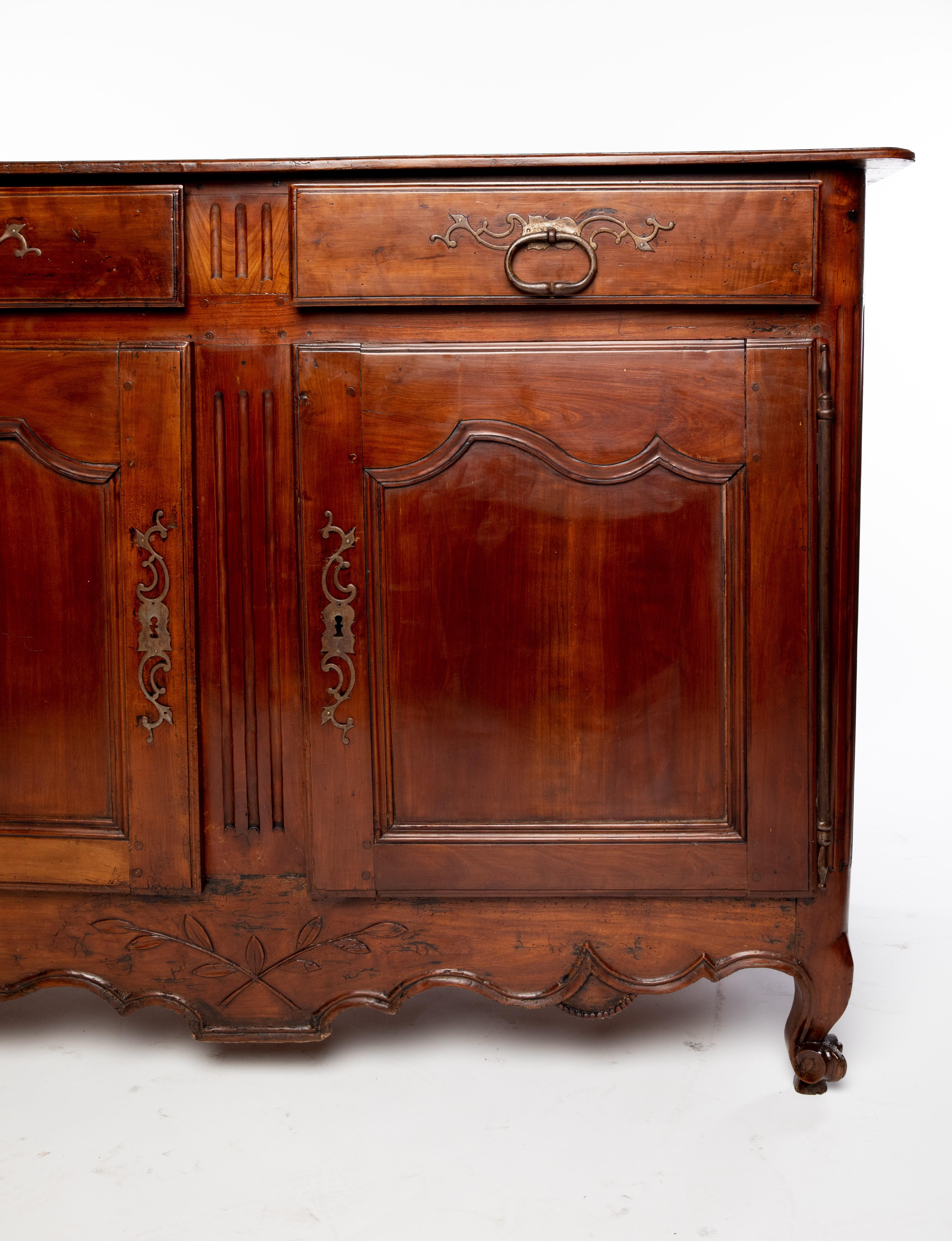 French Provincial Louis XV style fruitwood sideboard, 18th/ 19th c., rectangular case fitted with two drawers, over two cabinet doors on long exterior hinges, scalloped apron carved with crossed sprigs, rising on whorl feet, a separation between