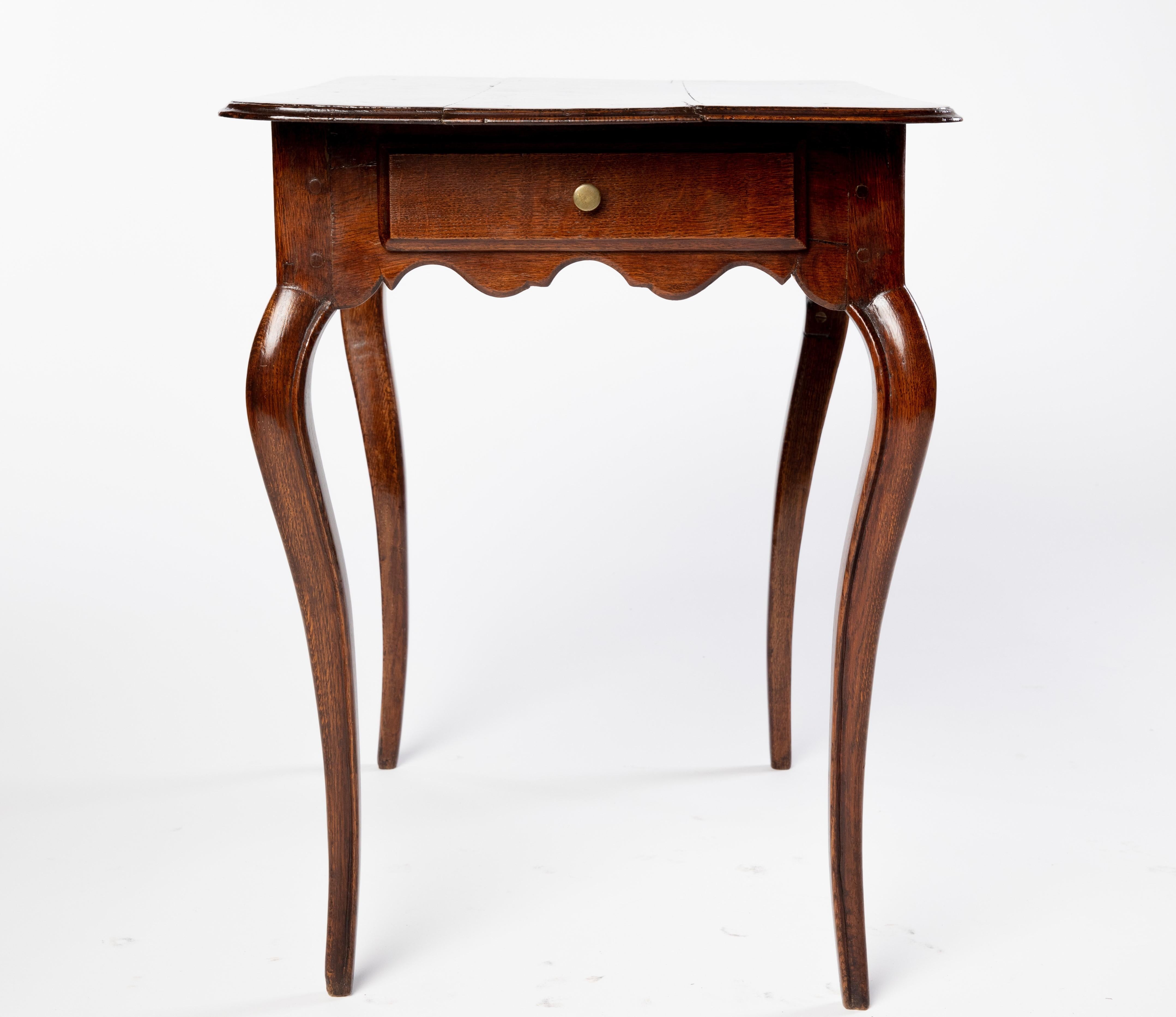 French Provincial Louis XV style oak table, early 20th c., paneled top over single side drawer, scalloped apron, rising on cabriole legs, splitting to top.