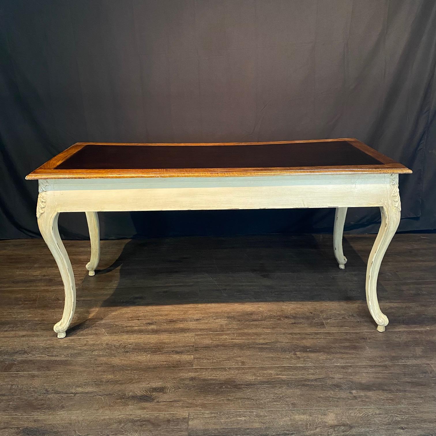 Elegant and spacious French Provincial Louis XV style writing desk with two drawers and white antiqued distressed ivory body, natural walnut top and ebony brown painted writing surface. Good original vintage condition. The desk is finished on the
