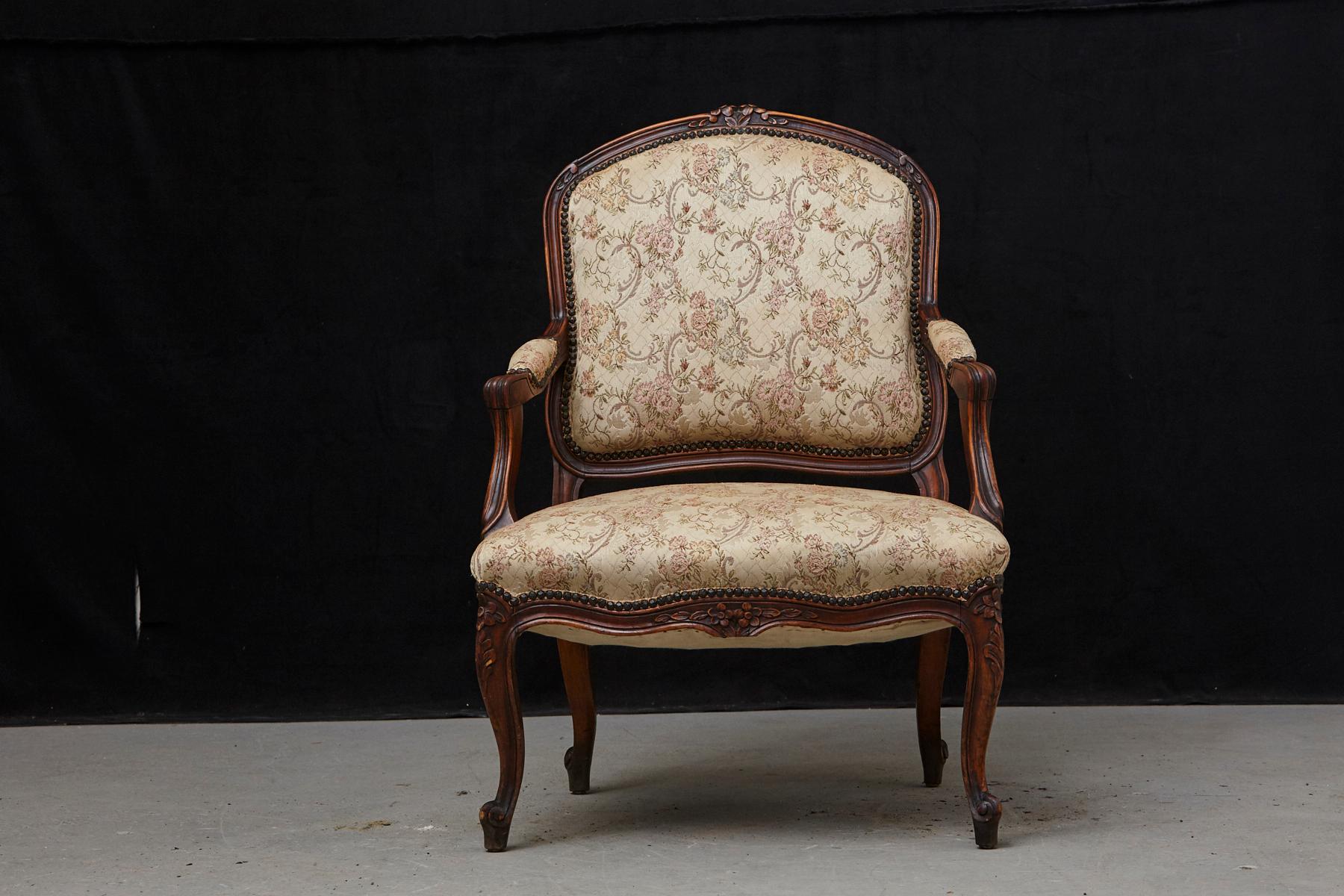 Lovely French Provincial Louis XV style walnut fauteuil, covered in nailhead trimmed fabric, with confirming armrests. The arms with voluted supports, carved apron, the whole raised on cabriole legs, circa 1930s
Some minor stains on the seat,
