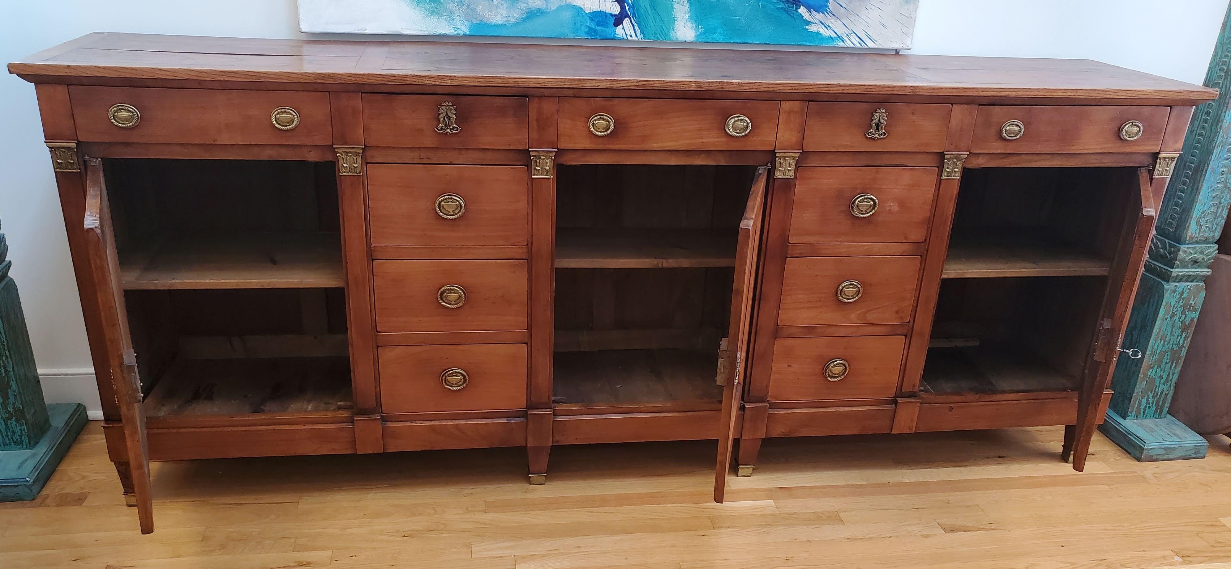 Fine quality French Provincial Louis XVI Enfilade (Long Buffet). Wonderful narrow proportions. Made predominately of richly patinated pearwood with a paneled top made of highly figured Elm. Three paneled cupboards and eleven drawers, all framed with