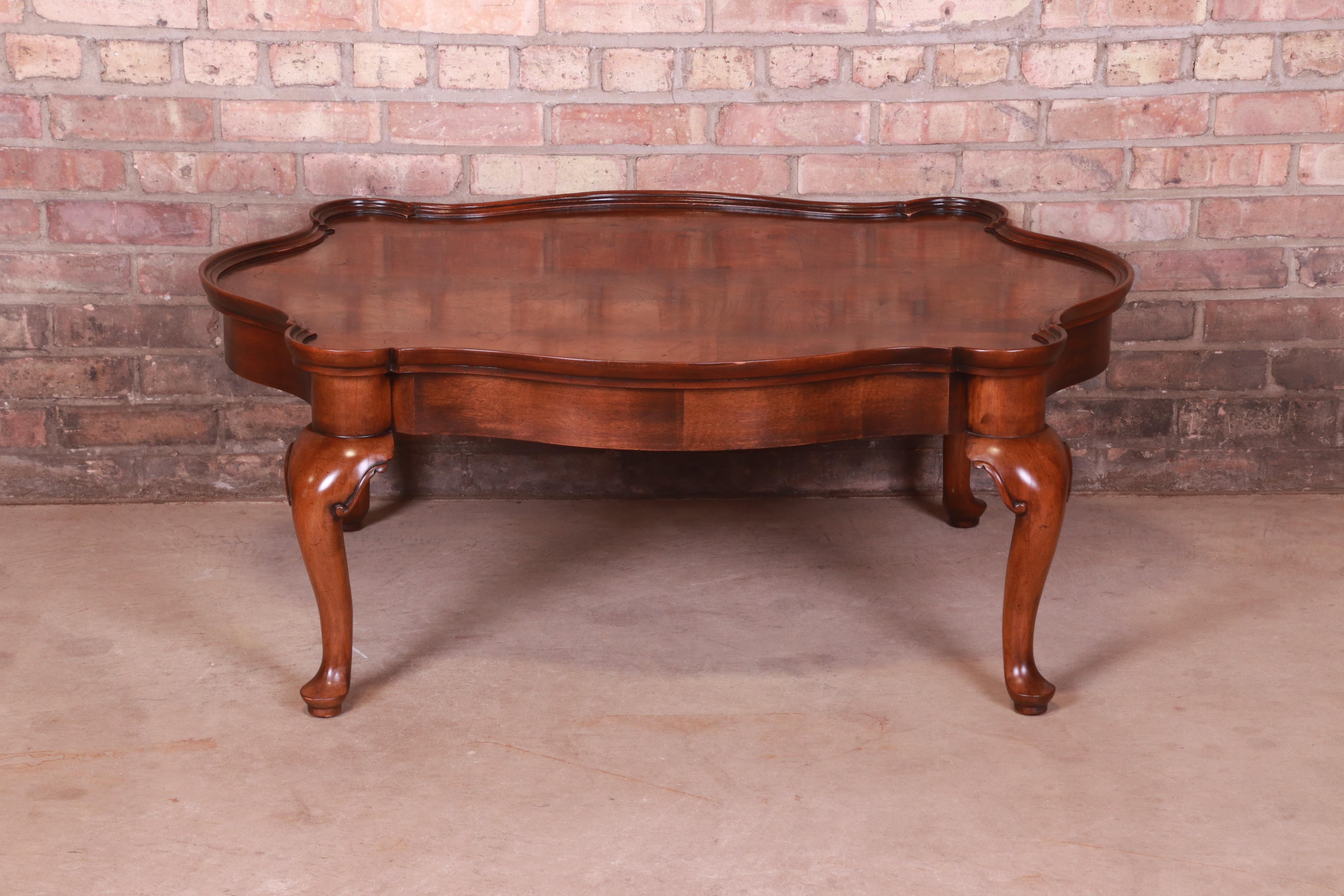 A gorgeous French Provincial Louis XV style coffee table

Attributed to Baker Furniture

Circa 1980s

Carved mahogany, with inlaid patchwork burled walnut top.

Measures: 43.25