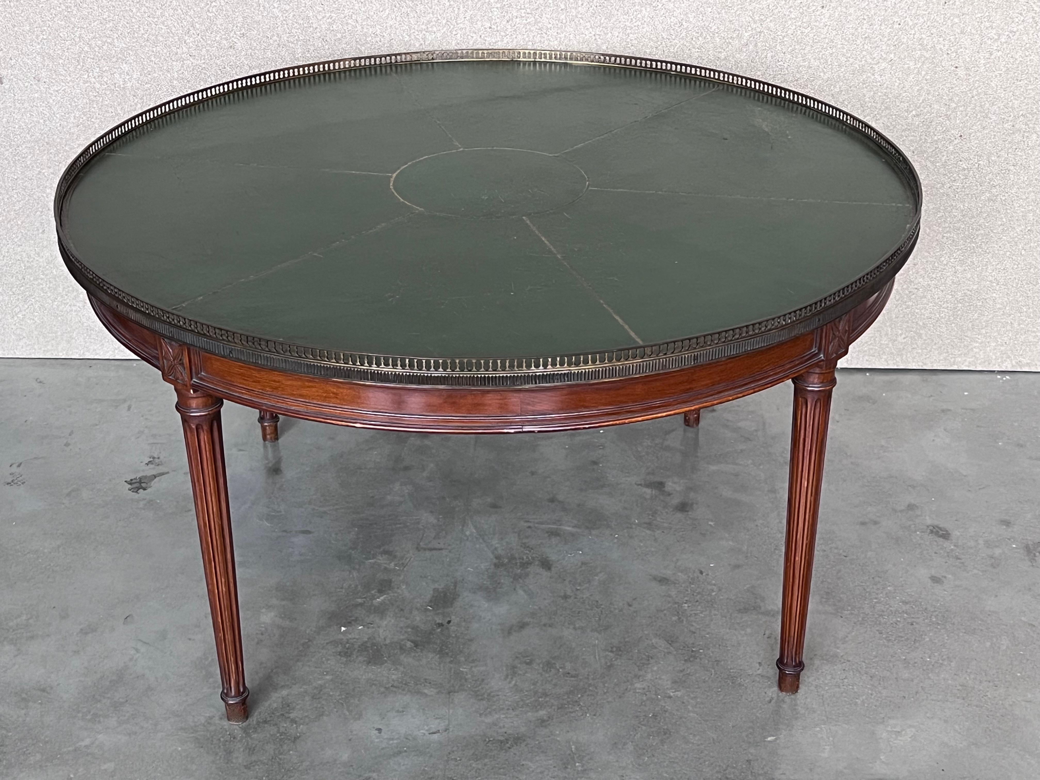 Handsome mid-century round green leather top mahogany coffee table with fluted legs. The table features a classic period style with a beautiful inlaid leather top and gold stenciling. An elegant, well-crafted piece in good vintage condition with