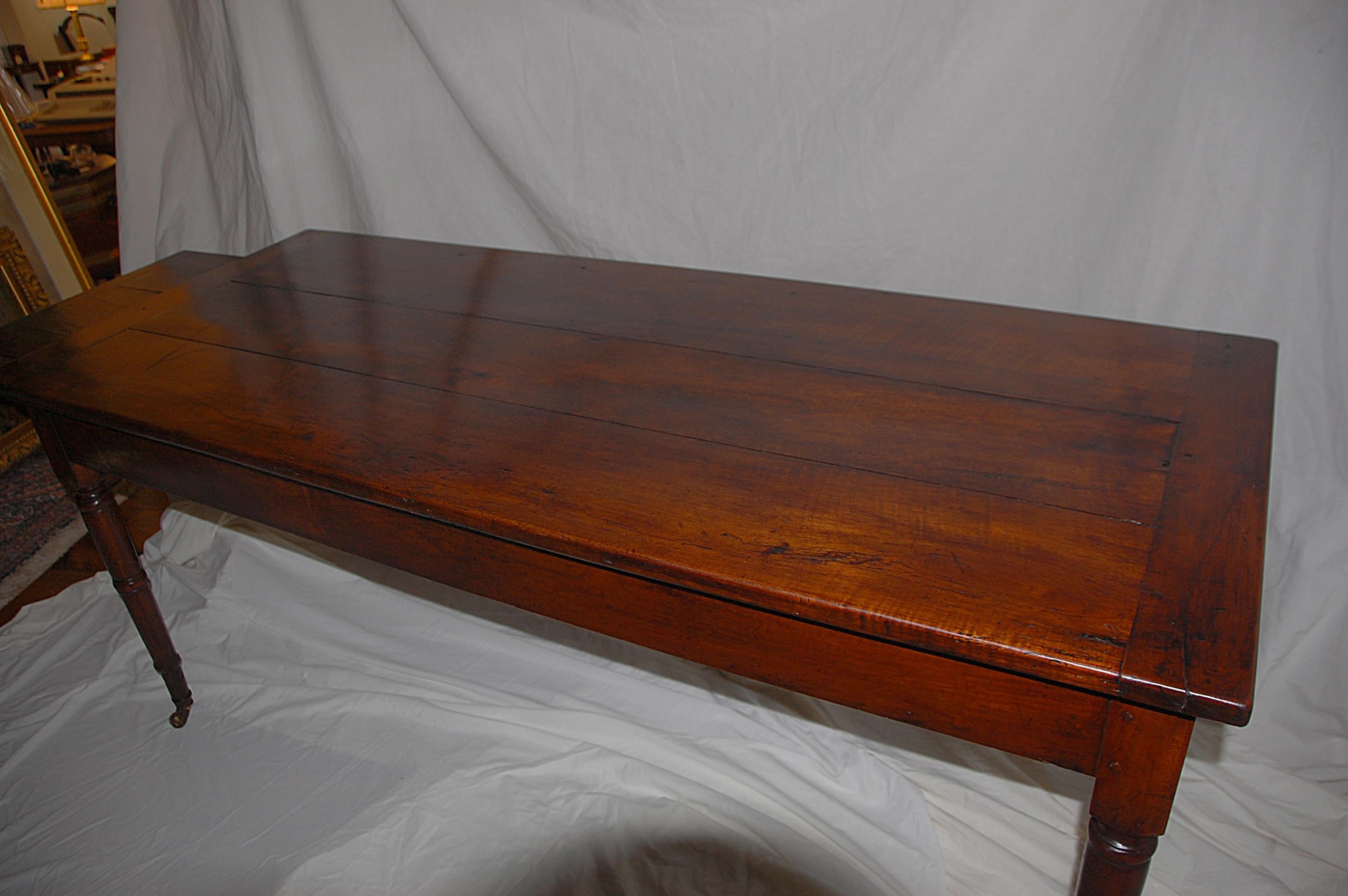 French provincial mid 19th century cherry farmhouse table with turned tapered legs. One end of the table has a large drawer, the other end has a breadboard pullout. This table has a wonderful mellow color and deep patination. At just under six feet