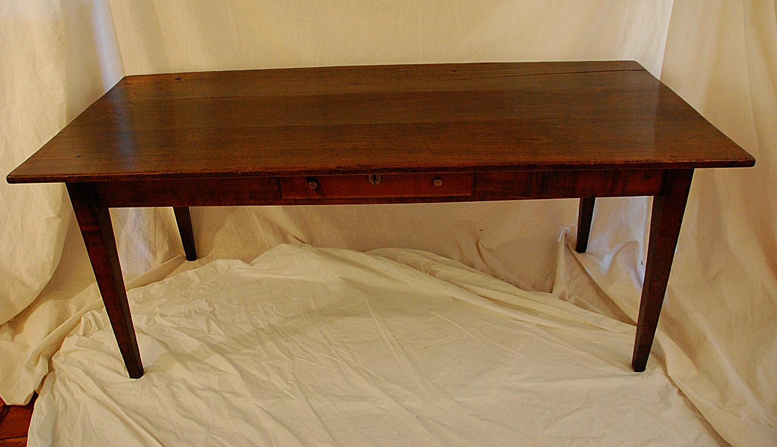 French provincial mid-19th century wild cherry farmhouse table with tapered legs, one side drawer, three board top. This six foot table easily seats eight and has the requisite 24 inch knee room all around; the 32 1/2 inch width makes for