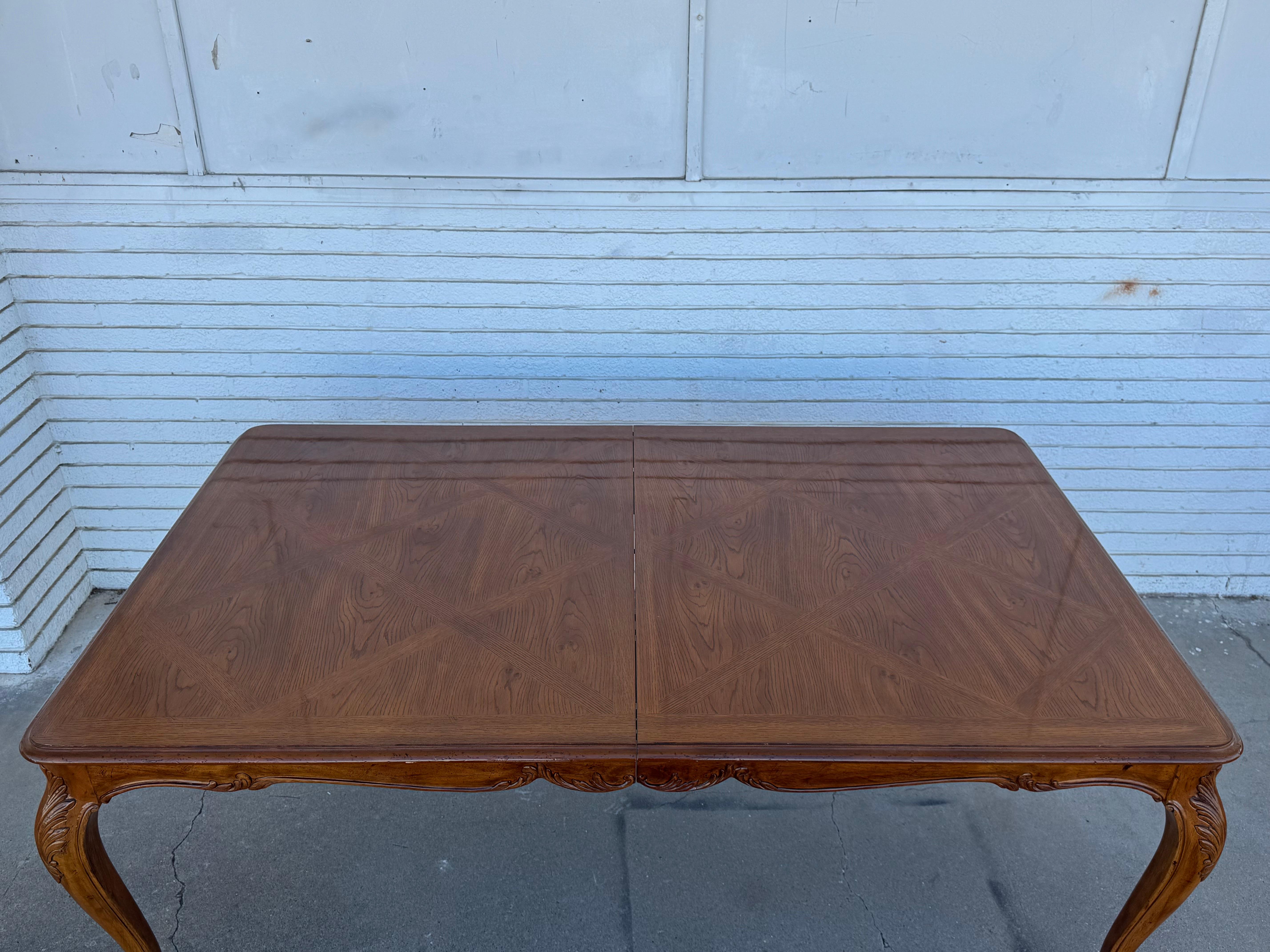 This is a large dining table. The top Is styled like parquet.
The elbows on the table are carved and they end in a bun foot.
It has 2 leaves that's 24 x 44 each.
The table extends to 120