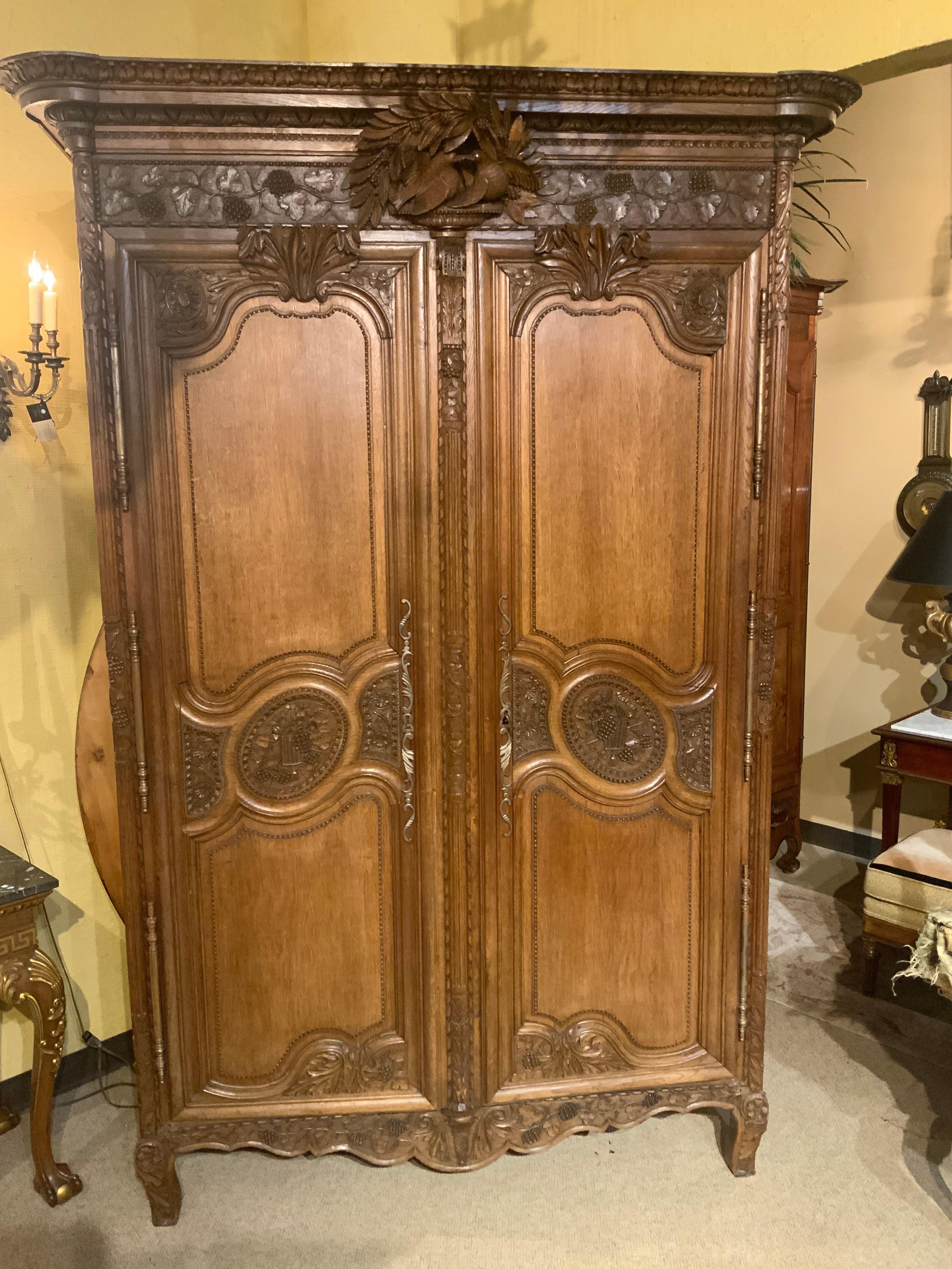This is a tall and elegant armoire hand carved in oak
With a carved pair of lovebirds and laurel crest, over
Scrolling grape vine motifs, dual cabinet doors with
Plaque of harvest basket, and elaborate foliate scrollwork,
Hung on long exterior
