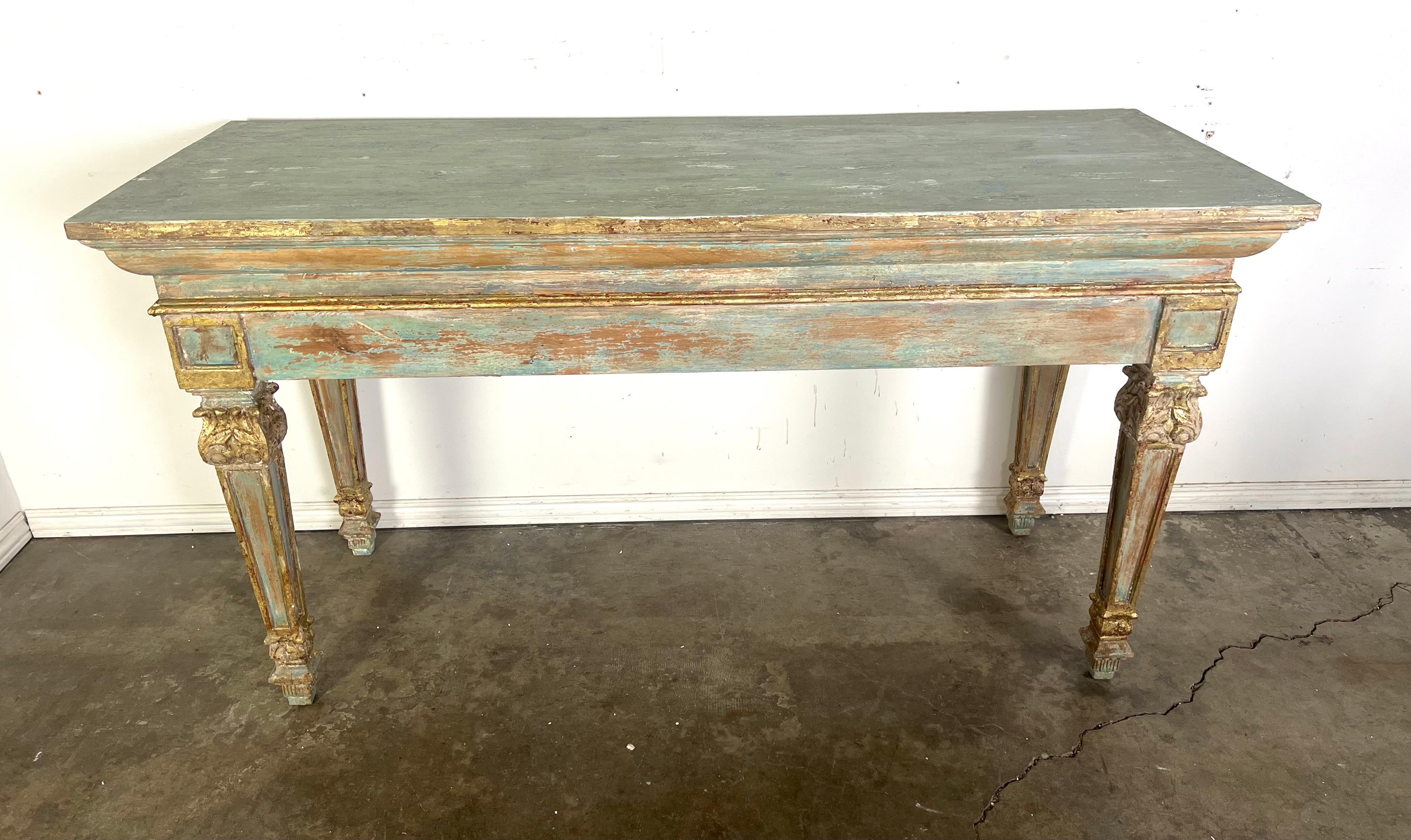 French Provincial style rectangular console table with a distressed, weathered finish.  The table features a classic design with straight lines and decorative, carved legs.  The finish is a combination of worn teal blue paint with areas of exposed
