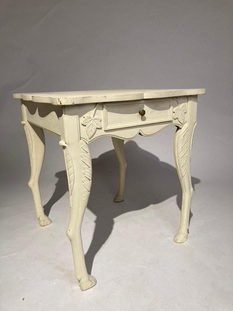 Wonderful white painted table with deer legs facing in towards each other. This whimsical design brings a smile to the face. Single drawer with ivy leaves carved in relief on either side. The shaped top adds to the overall pleasure of this lovely