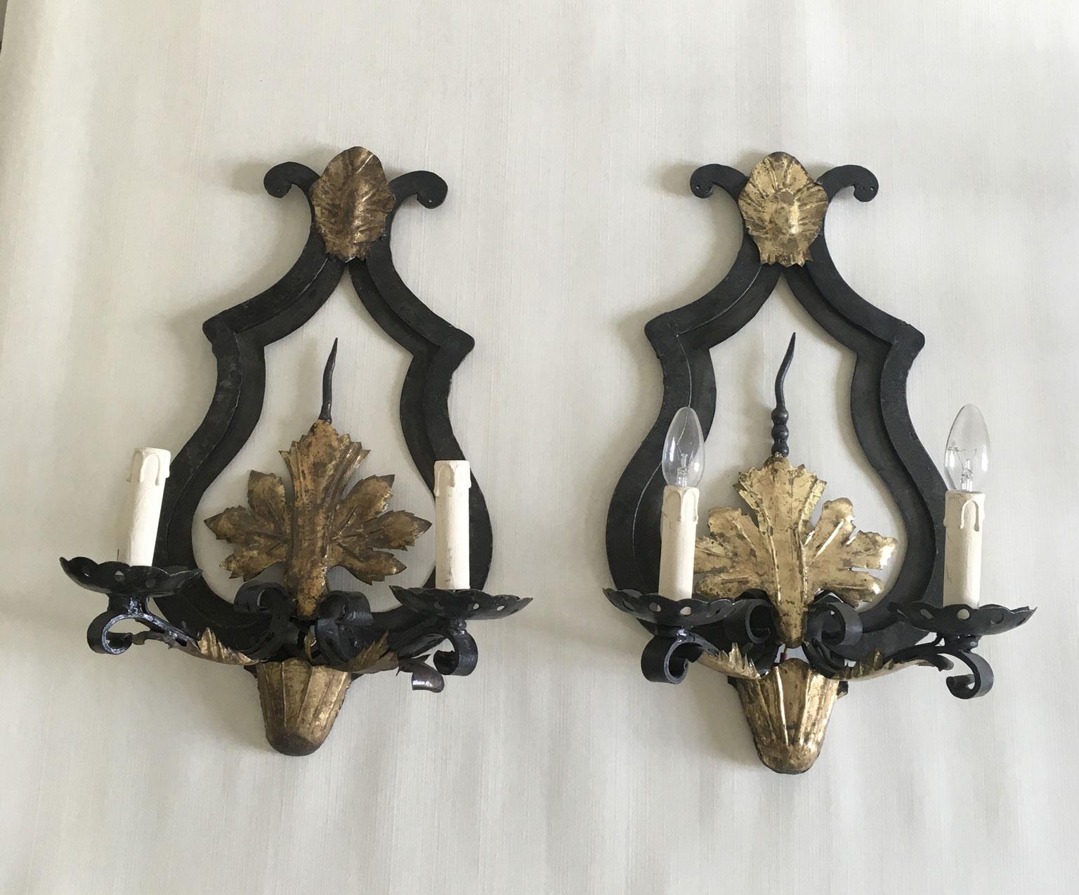 This French pair of  wrought iron wall lights, has a double bulbs each.
This elegant pair of wall lights is a contemporary production and it has an aged finish to look antique.
It can be used without lapmshades or with. In the second case, the wall