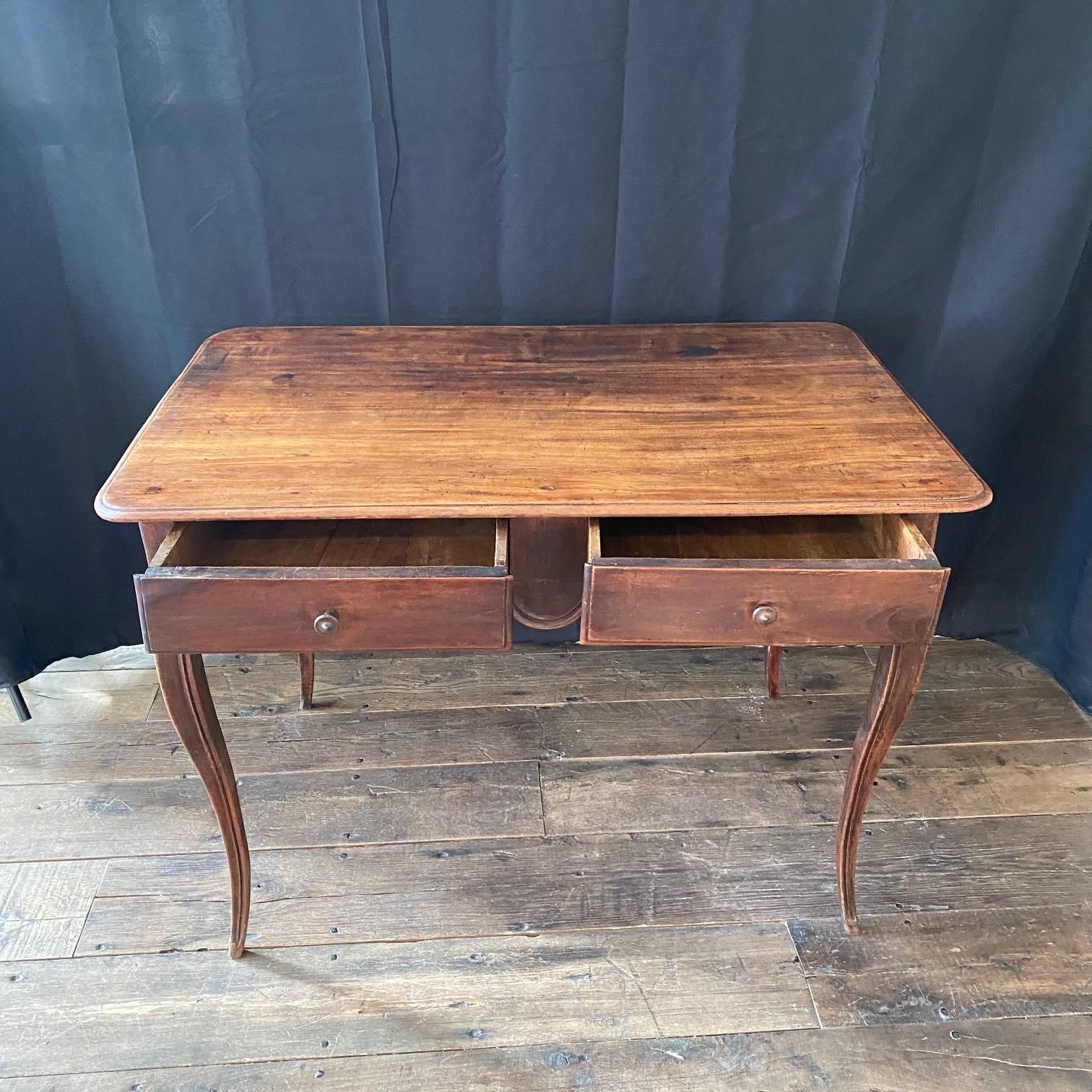 Lovely antique French side table or desk from the late 19th century; a beautiful example of the French Country design aesthetic. The table or desk has a beautiful carved scalloped apron on all four sides making it ideal to sit in the center of a