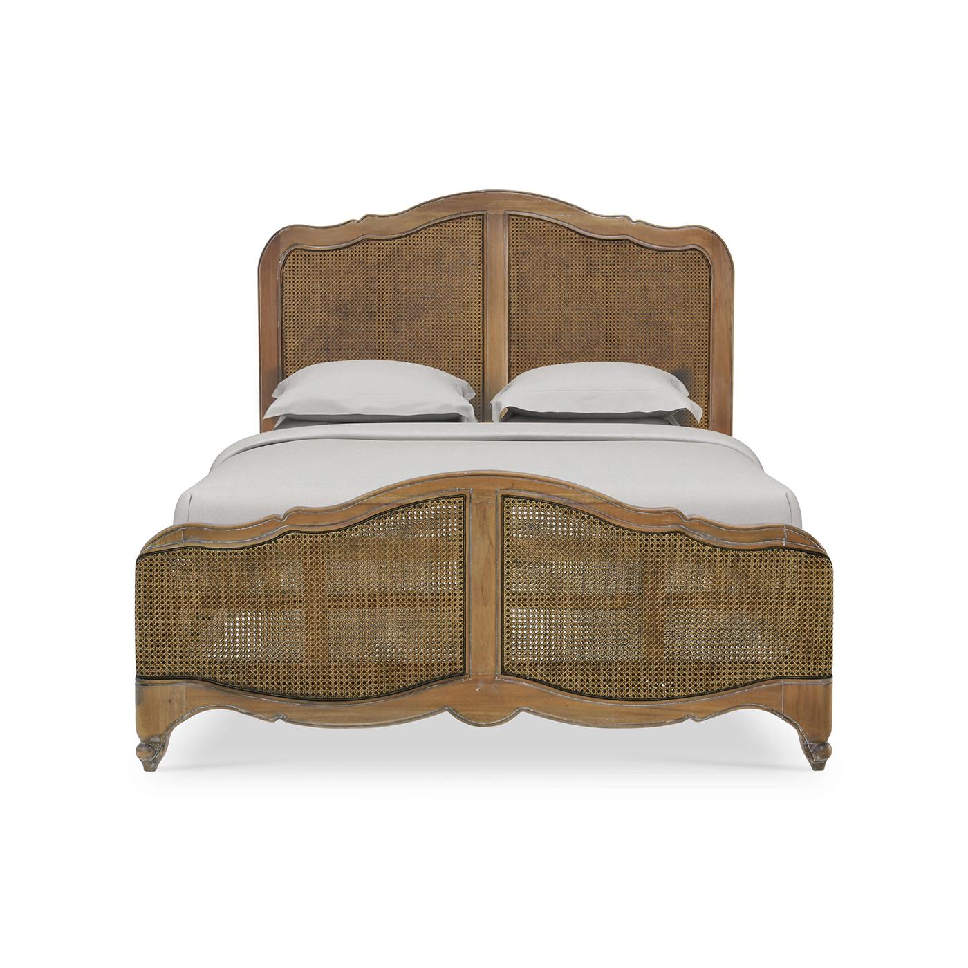 An 18th-century inspired, Louis XV-style carved bedframe, in a medium hand-rubbed and distressed Straw Wash finish.

The serpentine crest headboard features inset caned rattan in a glaze finish. The serpentine footboard with inset rattan and curved