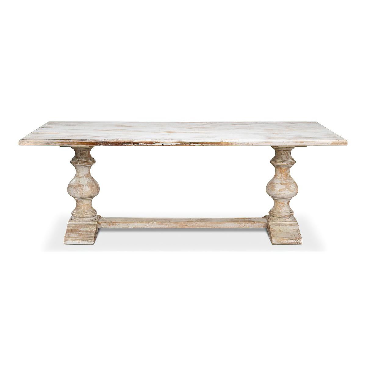 A French Provincial refectory table with a unique distressed white painted finish.  With a molded edge and raised on baluster turned legs in a trestle form with a stretcher. 

Dimensions: 84