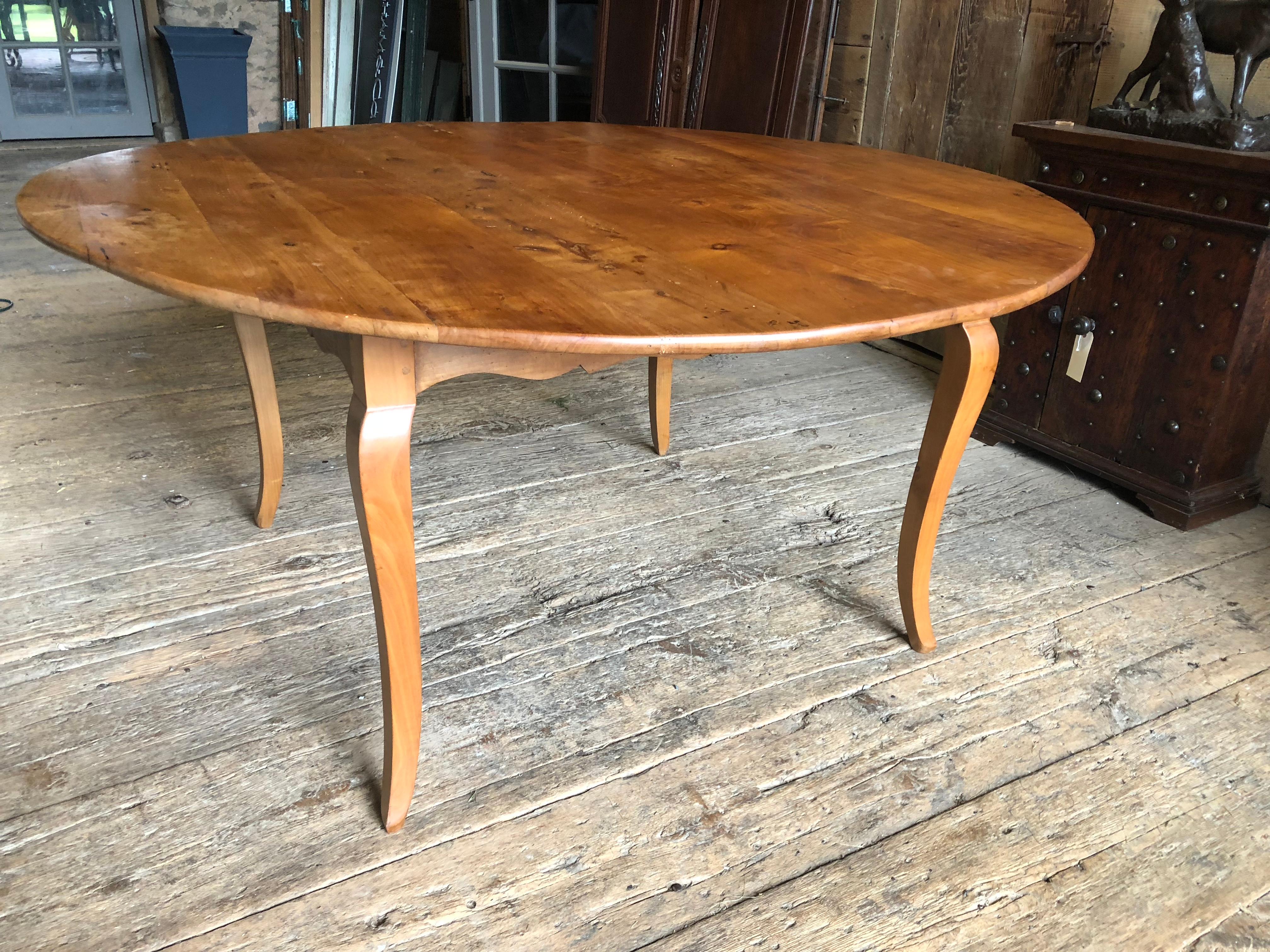 A large round French farm table in cherrywood with Louis XV style cabriole legs and scalloped apron, probably mid 19th century, refinished. Has old shipping label “Desbordes Epoche LXV”.