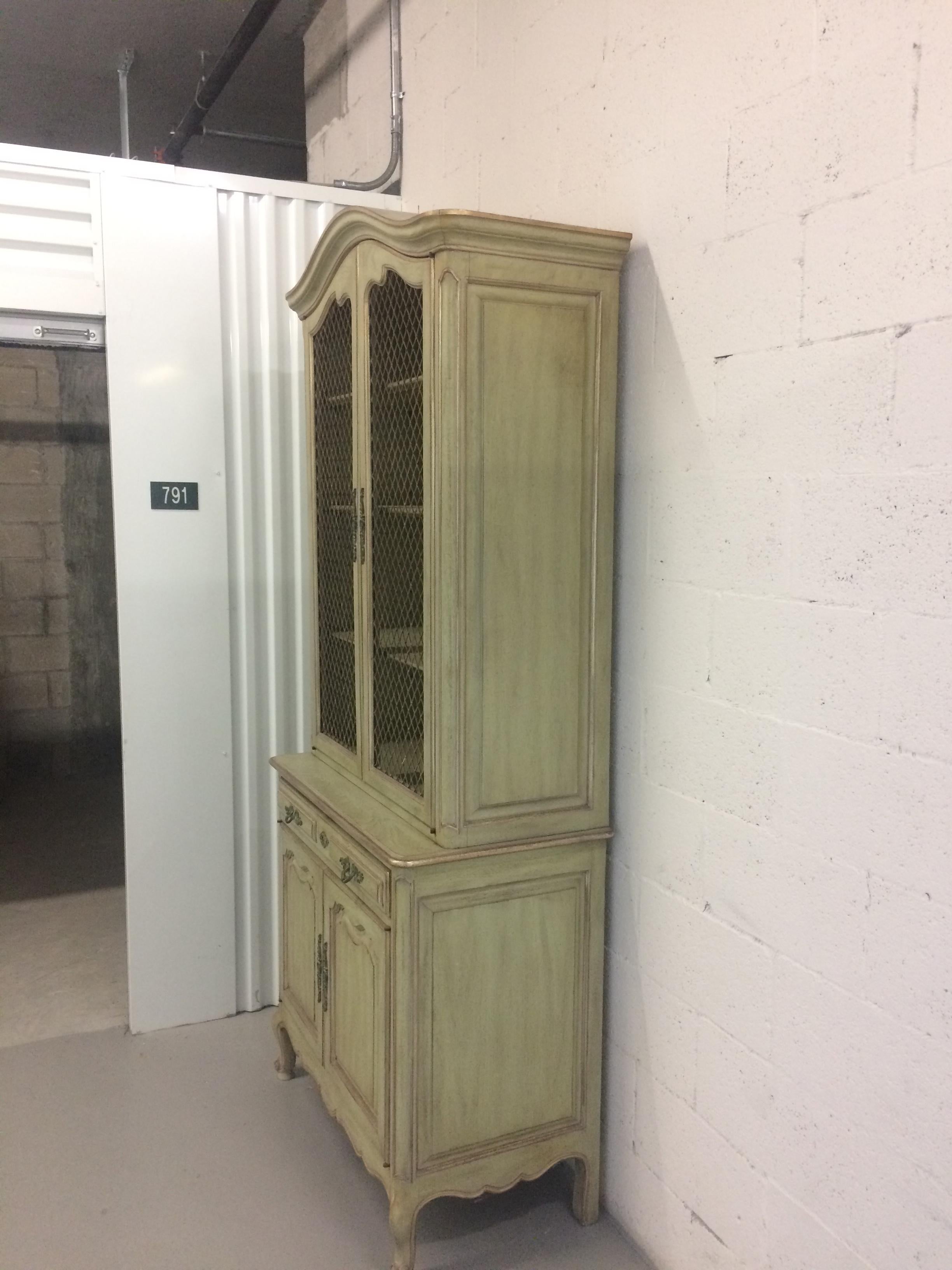 French provincial style 3-drawer step-back cupboard. Drawers below with open mesh doors above with illuminated shelves. Has the original pickled green paint with silver high lights in very good condition. Most of the old world Palm Beach mansions