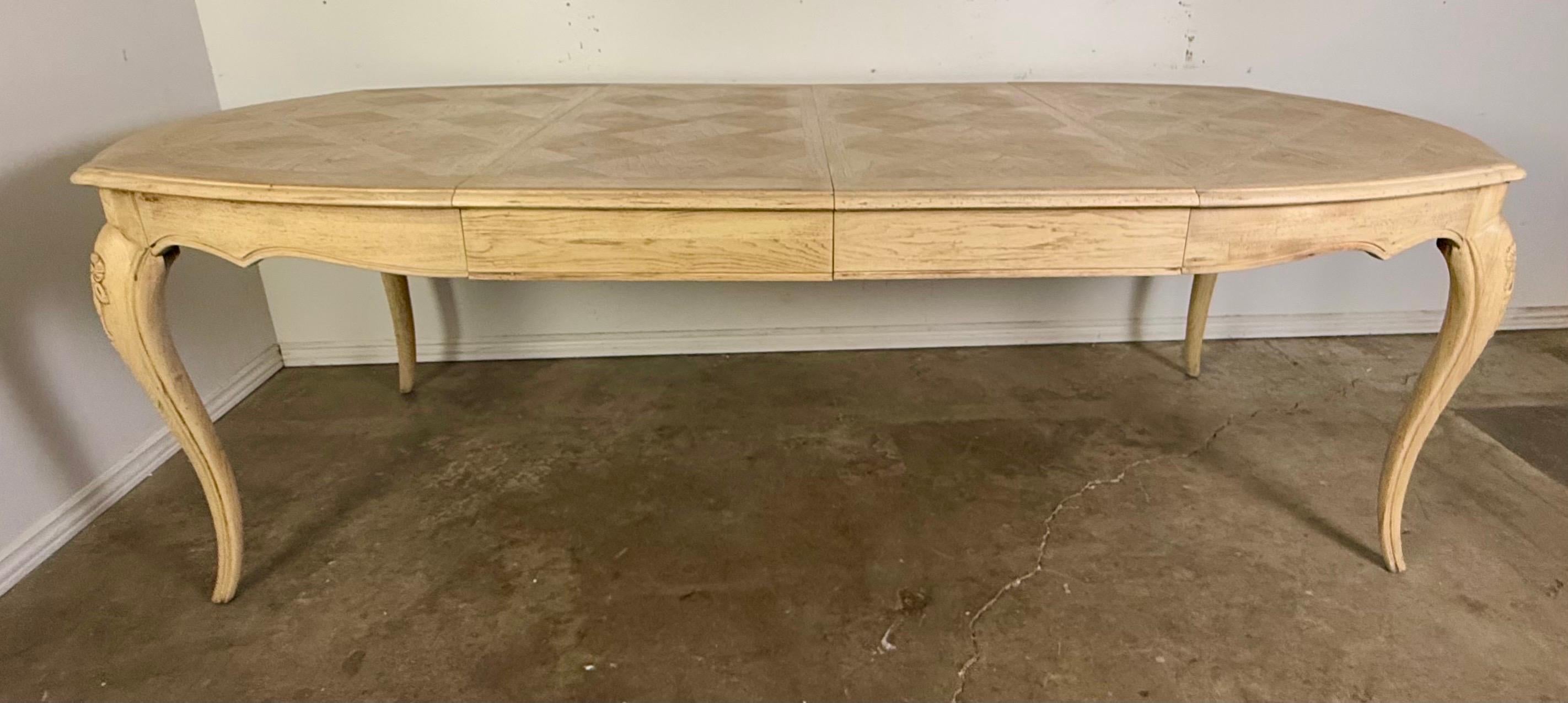 Mesa de comedor de estilo provincial francés con un diseño elegante y clásico.  La mesa se alza sobre cuatro patas cabriolé, cada una adornada con delicadas tallas florales cerca de la parte superior, una firma de la estética provincial francesa. 