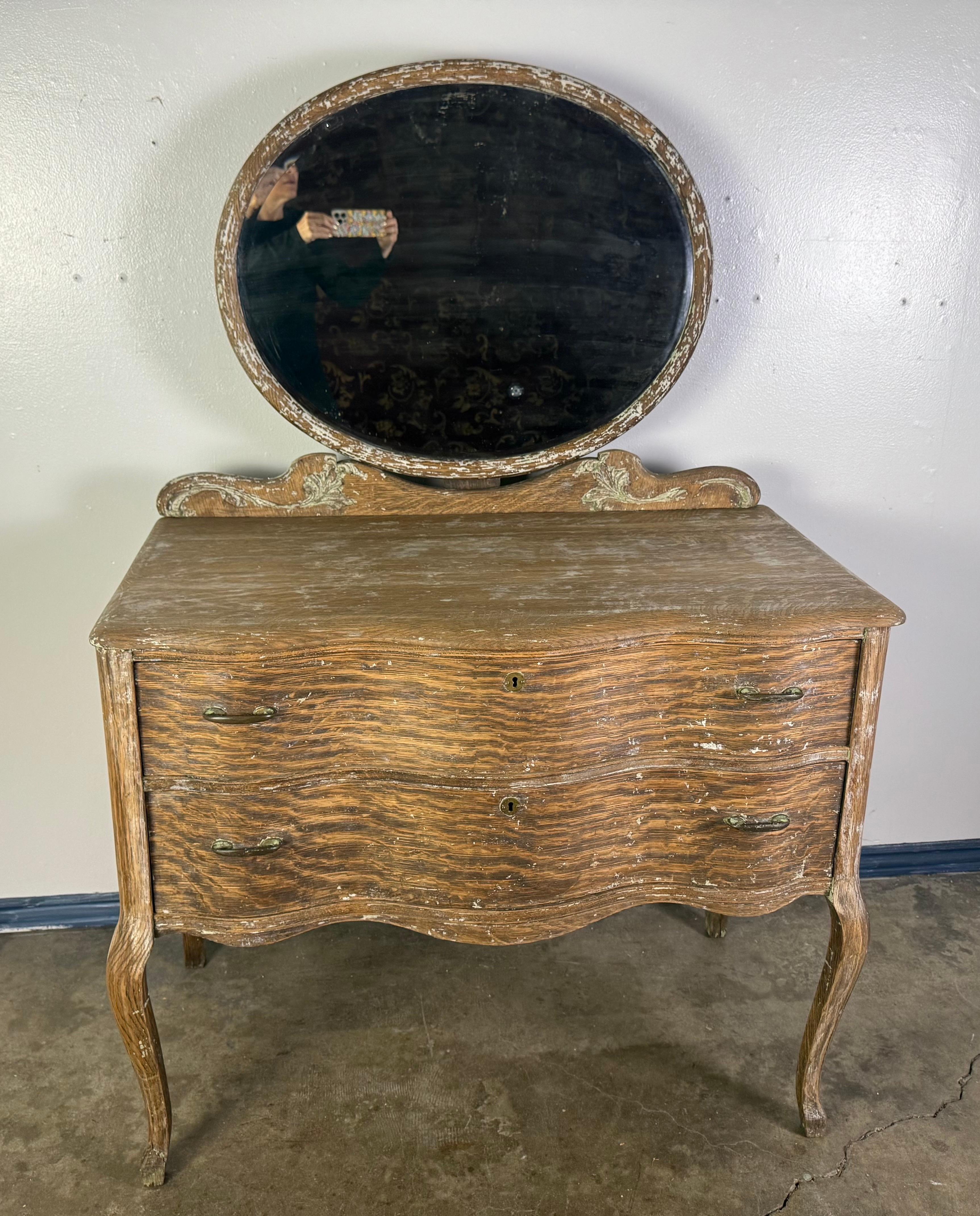 This is a charming 19th century French chest of drawers with attached mirror, crafted in a French Provincial style, likely dating to the mid-to-late 1800s. The piece features the quintessential curving lines and graceful silhouette of the Rococo
