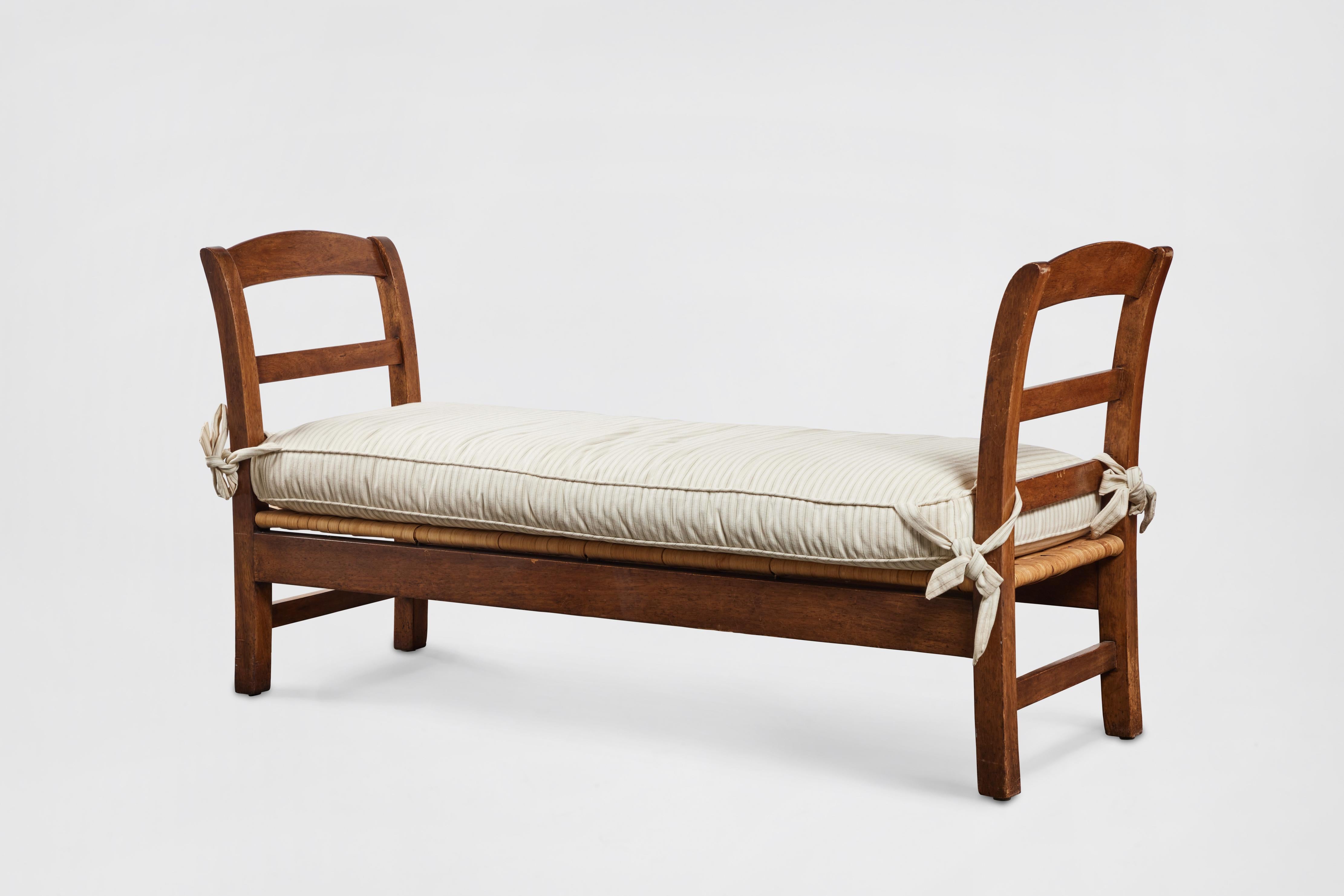 French Provincial style mahogany bench or daybed with striped ivory/beige linen cushion and wicker seat base. Cushion has ties to secure it in place. Made in 1995 by John Hall Designs, Los Angeles

Additional Dimensions: 
Seat Height 13