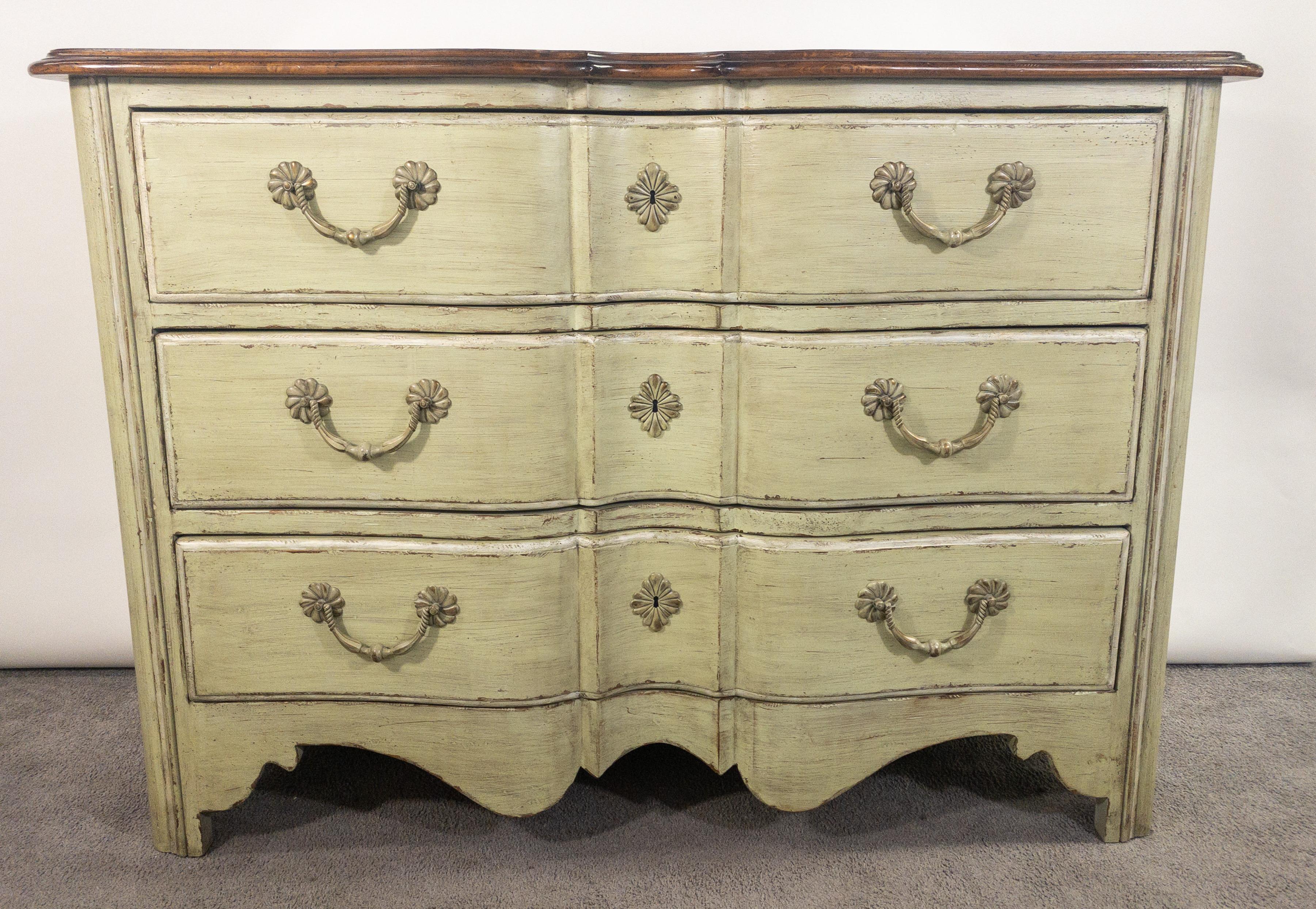 A French provincial style commode or chest having three large drawers. The quality commode is made by Walter E Smith and is marked inside the first drawer. The commode or chest features a beautiful light green color and a solid mahogany top with two