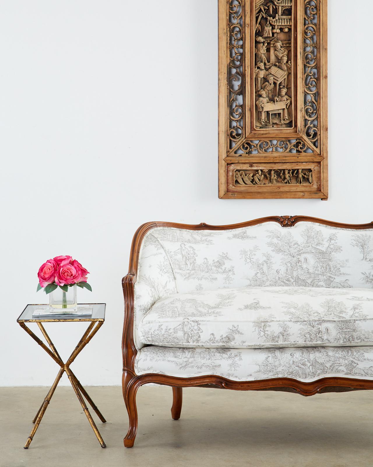 Exquisite French canapé or settee made in the Provincial or Louis XV style. Features a carved walnut frame with a serpentine crest rail and apron. The molded arms gracefully curve down to the seat which is topped with a loose seat cushion.