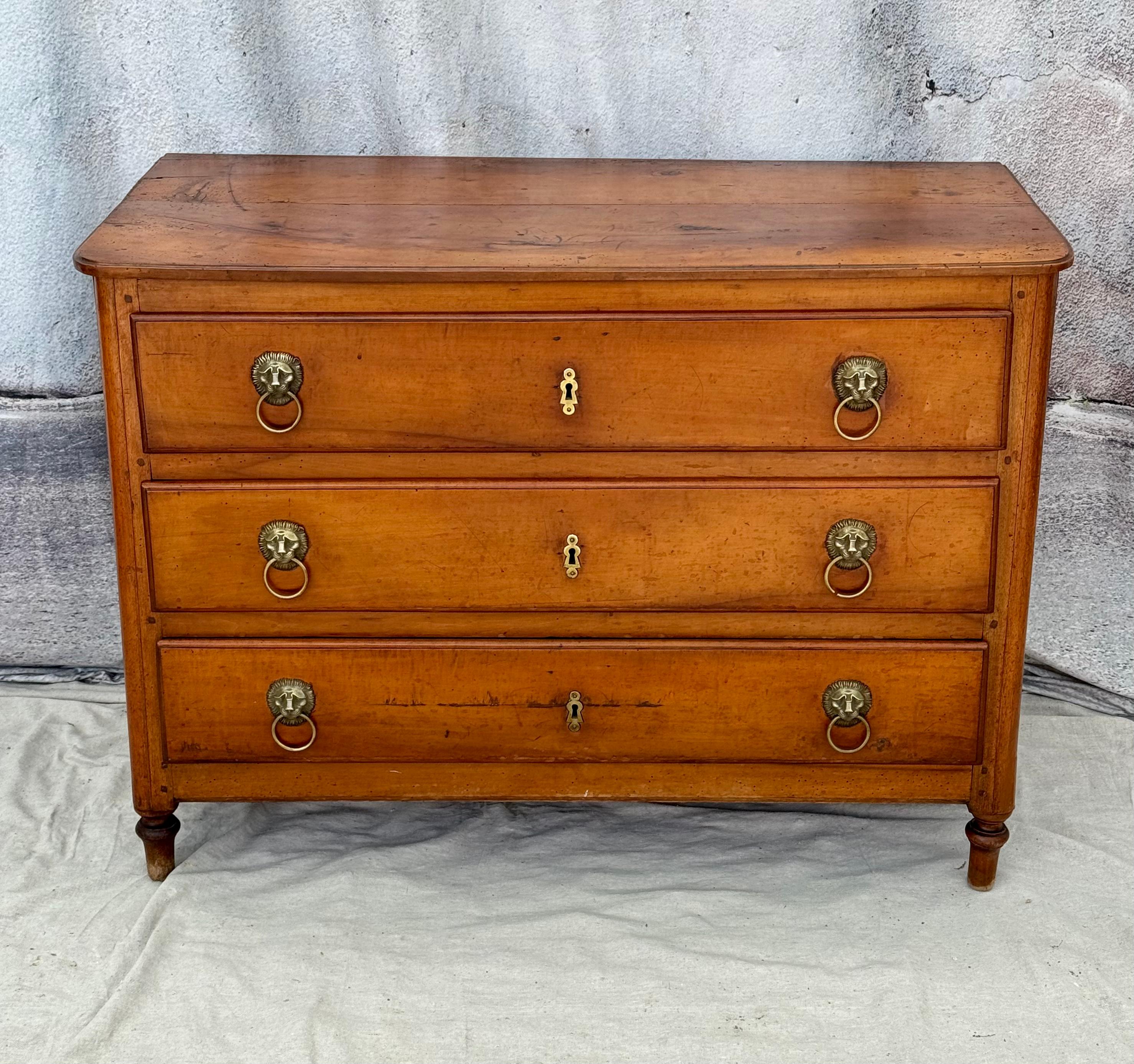 Early 19th century French Provincial Directoire chest. Chest features three drawers with lion head pulls, all rising on turned legs. Wonderful old finish with a mellow patina.