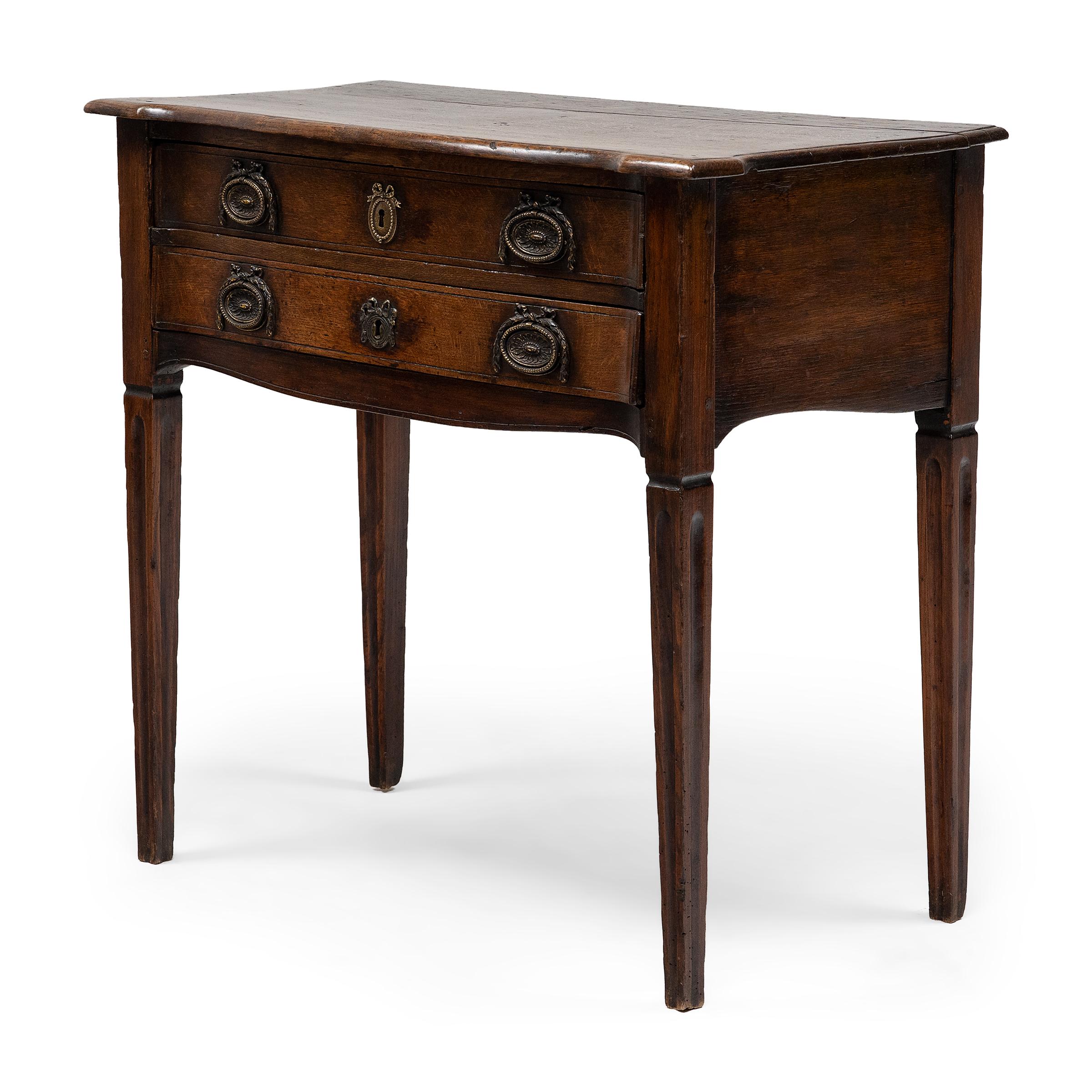 This two-drawer side table is crafted of oak in the French Provincial style, blending the refined elegance of classical French furniture with the timeless simplicity of country furnishings. Dated to the late-18th century, the table reflects a
