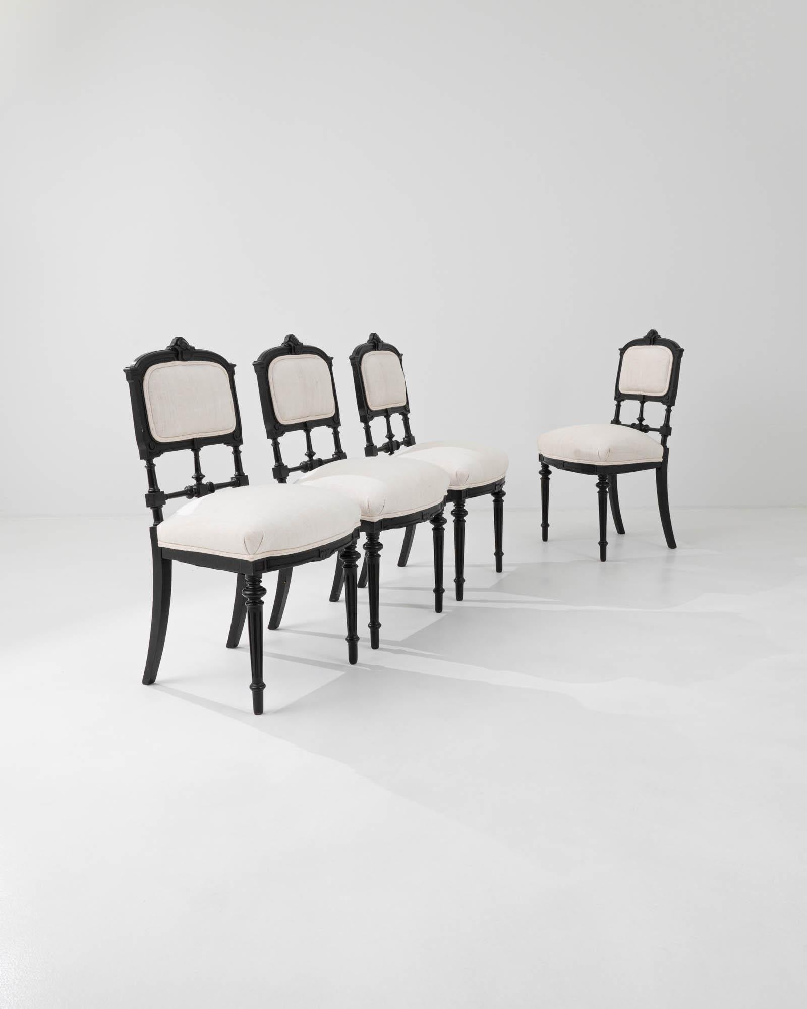 These antique chairs from nineteenth century France are finished in ebonized lacquer and re-upholstered in a contrasting ivory-coloured fabric. Eclectic and heavily ornamented with turned legs and backs, this set would bring an elegant and nostalgic