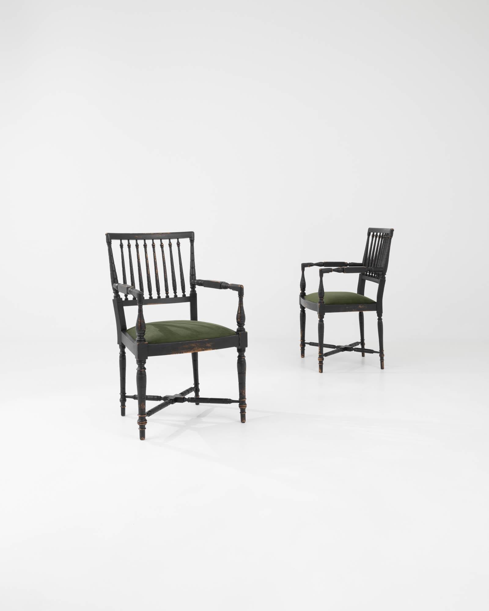 Made in France in the 20th Century, this pair of side chairs is constructed from lathed wooden elements, and re-upholstered with a velvety green fabric. The black finish, devoid of color, serves to highlight the form of the carving. The shapes