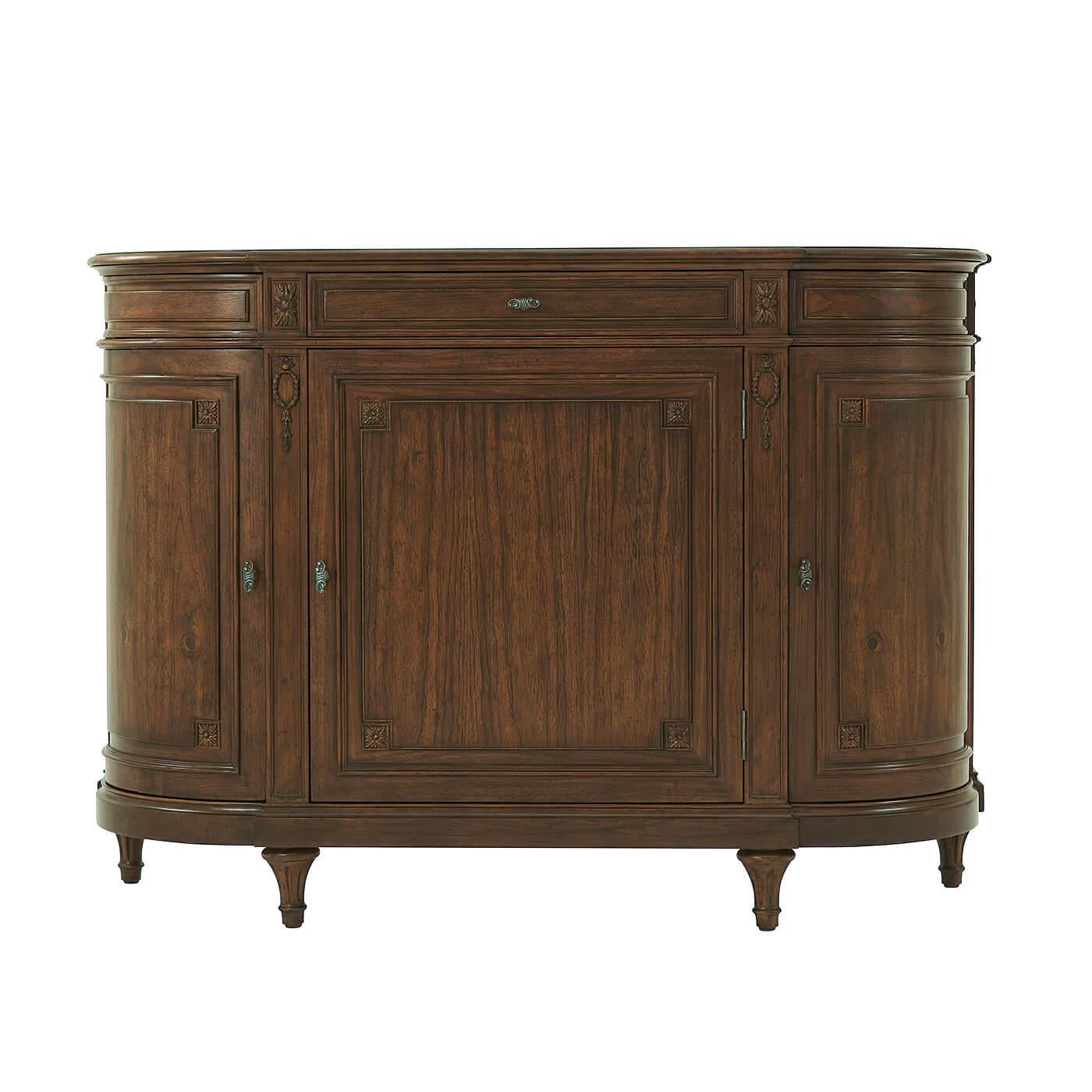 A French Provincial walnut buffet in a demilune form, with a molded and shaped top edge, with a long central frieze drawer, above a three-door cabinet section with shelves to their interiors, also with carved rosettes and raised on a molded base