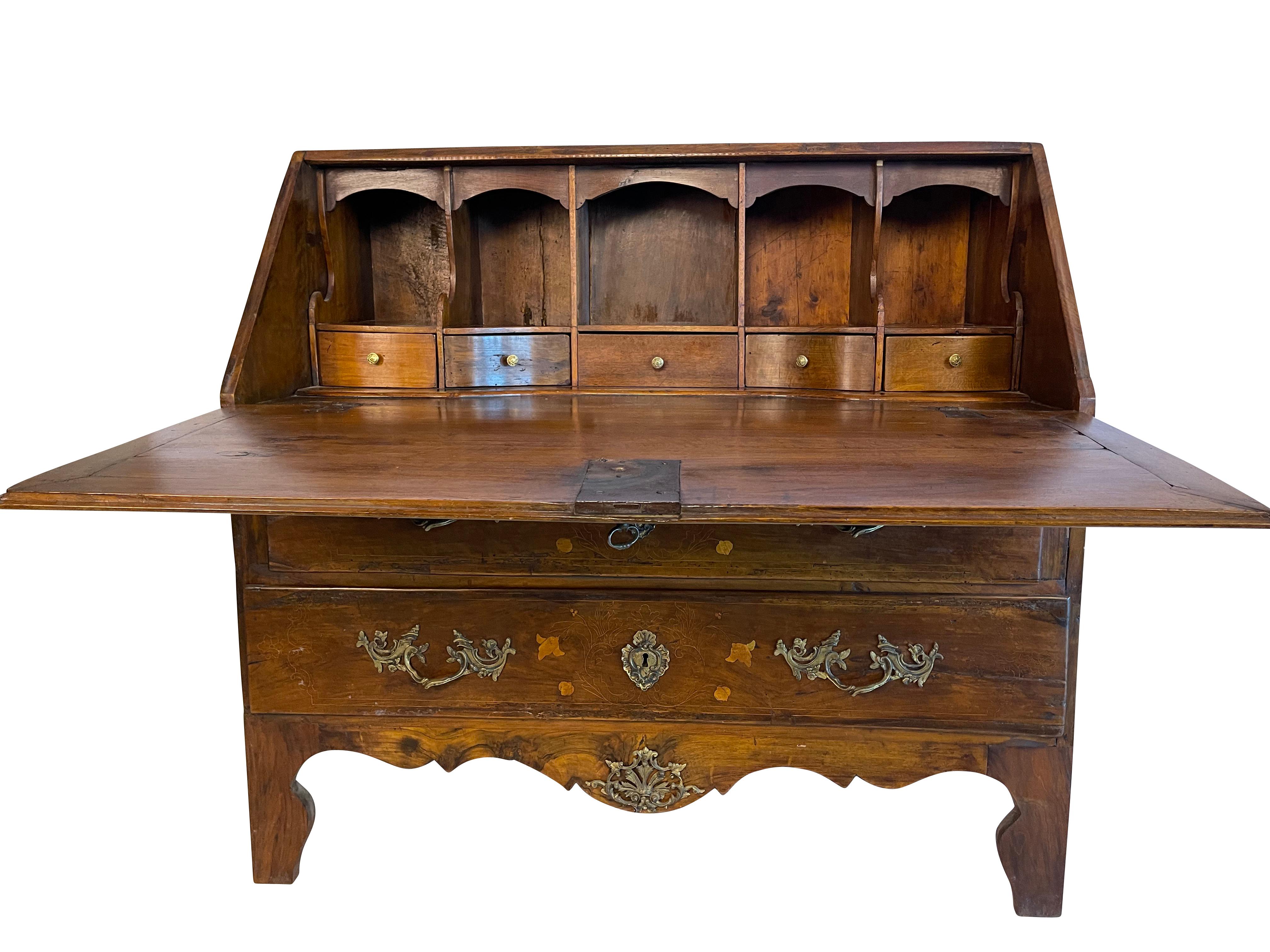 A stunning French solid walnut commode with a fold-down secretary desk housed in its top drawer. The secretary is decorated with satinwood inlays throughout. The two drawer fronts have elegant brass pulls and decorative escutcheons. The top