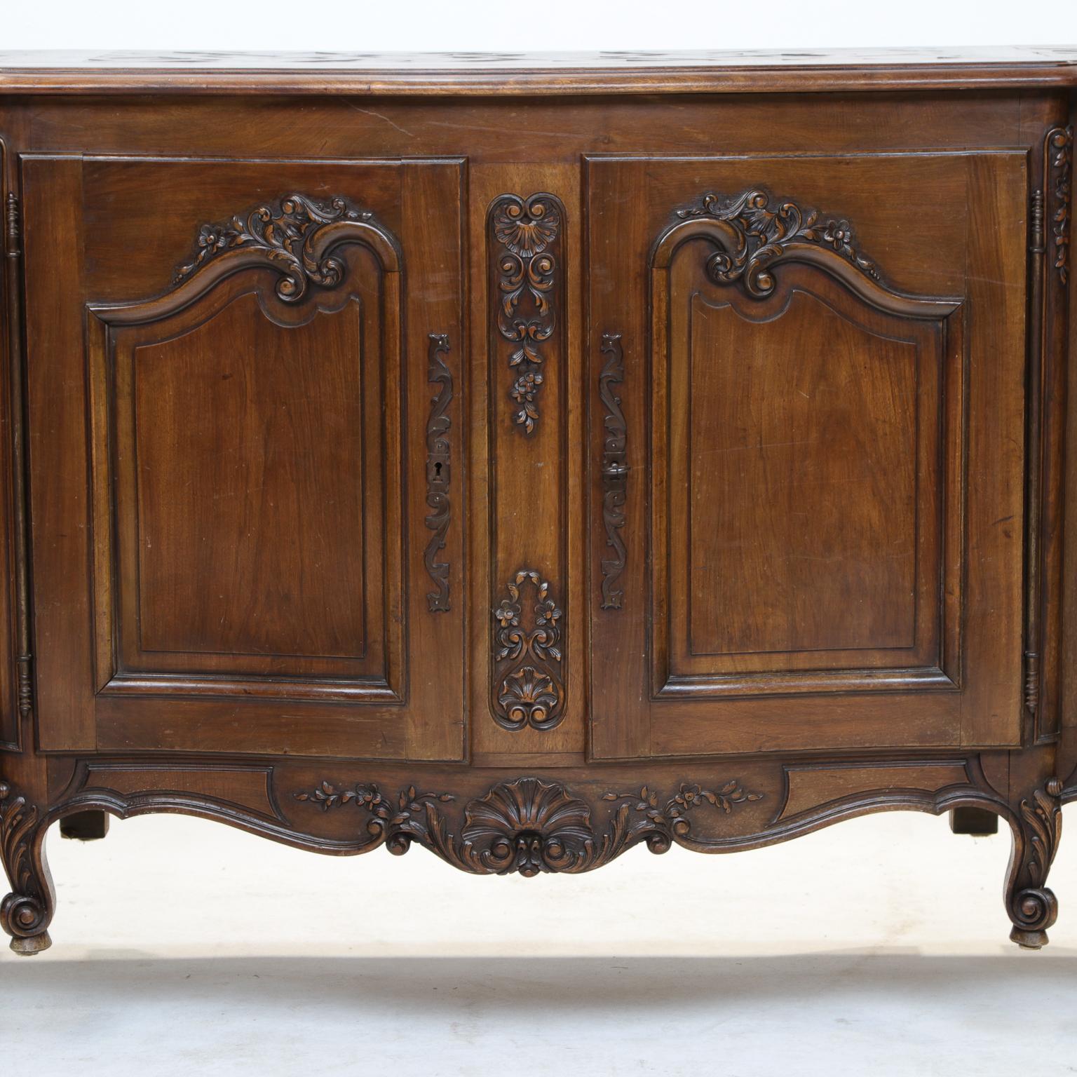 A fine French Provincial walnut Enfilade. Nice carved panel doors. 4 doors open to shelves with ample storage. The top has parquetry work and breakfront. Nice carved apron and resting on scroll legs.