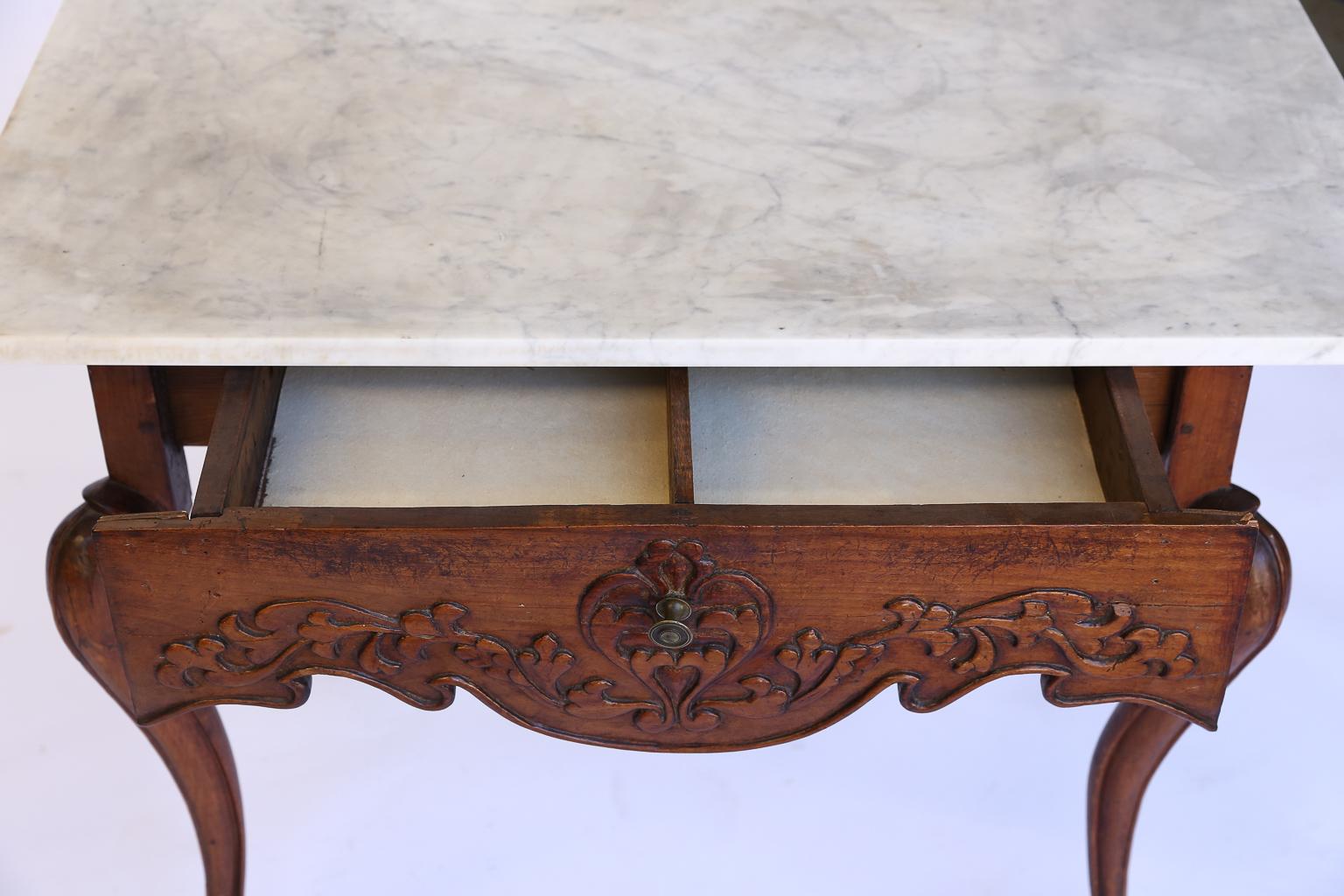 We found this charming French walnut end table in Provence. The table has a beautifully carved scalloped drawer on the front and cabriolet legs. The gorgeous wood patina on the base of the piece is one that can only come with age. The top of the