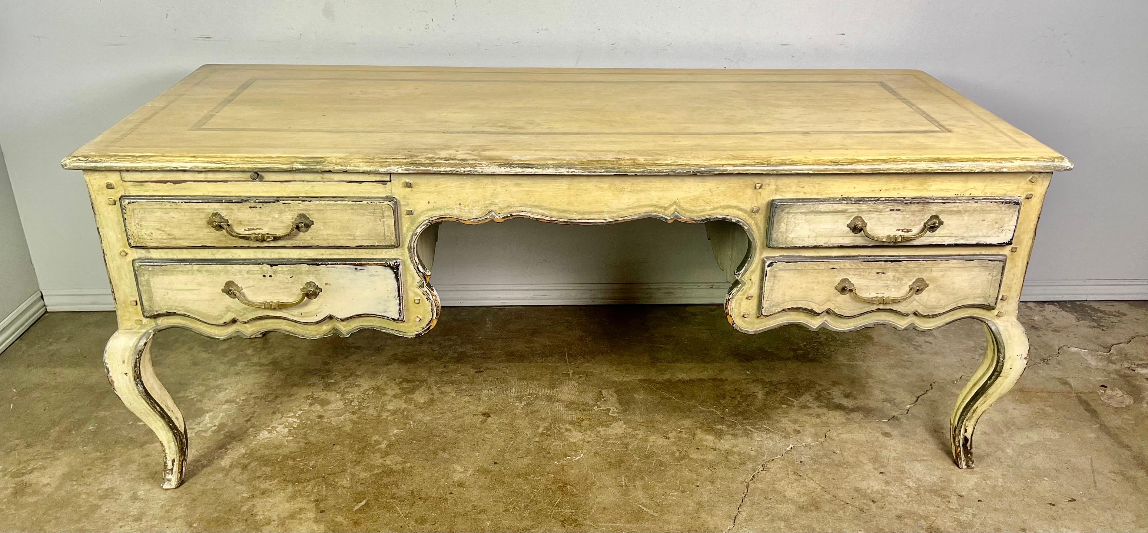 Early 20th century painted French Provincial style desk. The desk stands on four cabriole legs that end in rams head feet. The piece is beautifully painted in a worn. Faded finish. There are four functioning drawers and a slide out shelf on one side