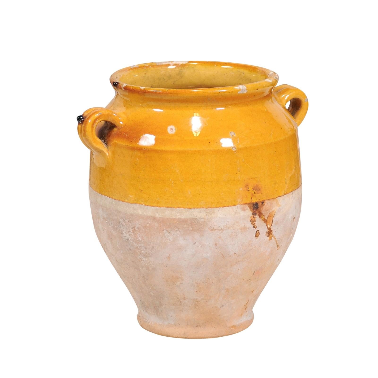 A rustic French Provincial pot à confit from the 19th century with yellow glaze and double handles. Step into the rustic charm of the French countryside with this authentic 19th-century French Provincial pot à confit, a piece that encapsulates the