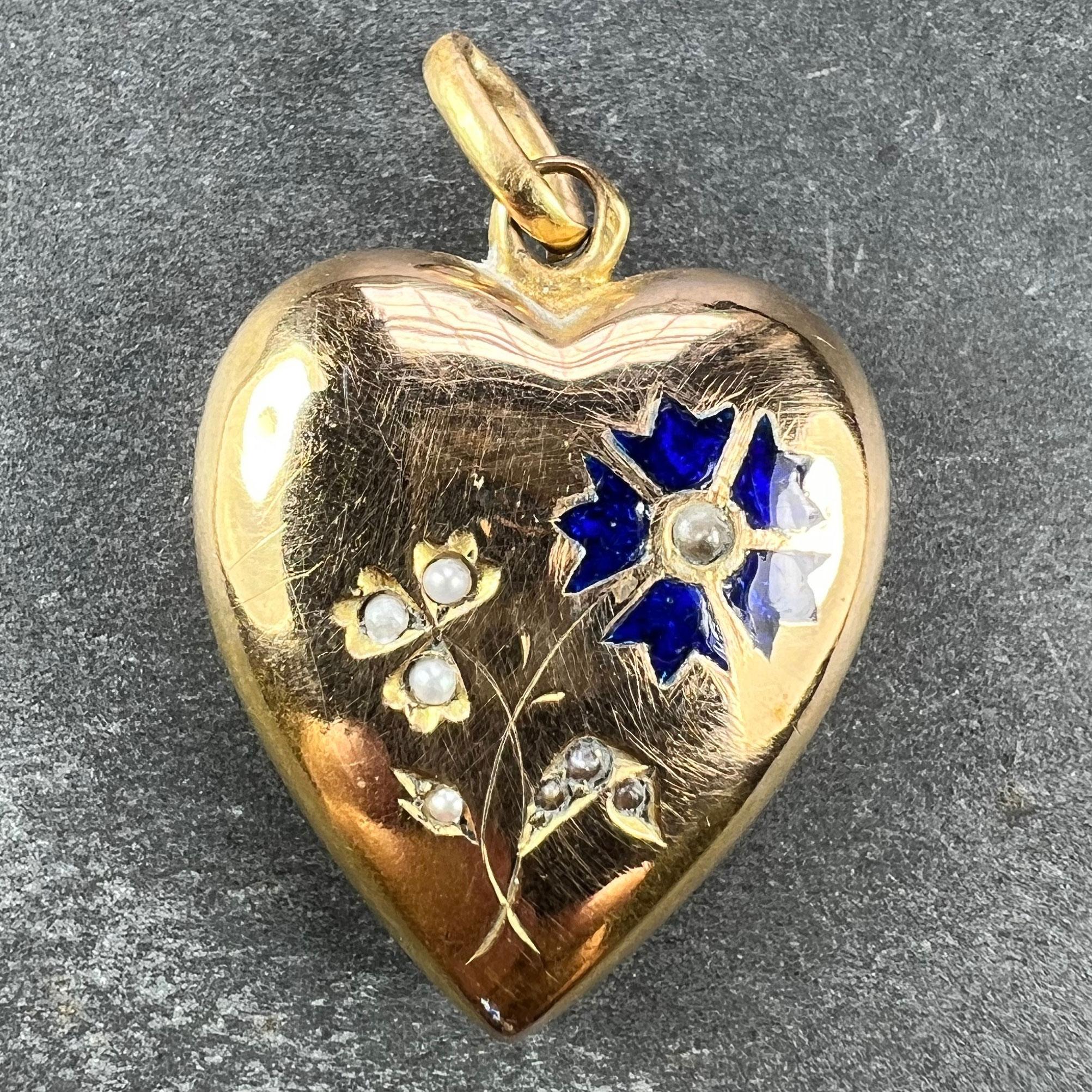 A French 18 karat (18K) yellow gold charm pendant designed as a puffy love heart engraved with a flowers being a white bud and a cornflower in bloom, set with white natural seed pearls and blue enamel. Stamped with the eagle's head for 18 karat gold